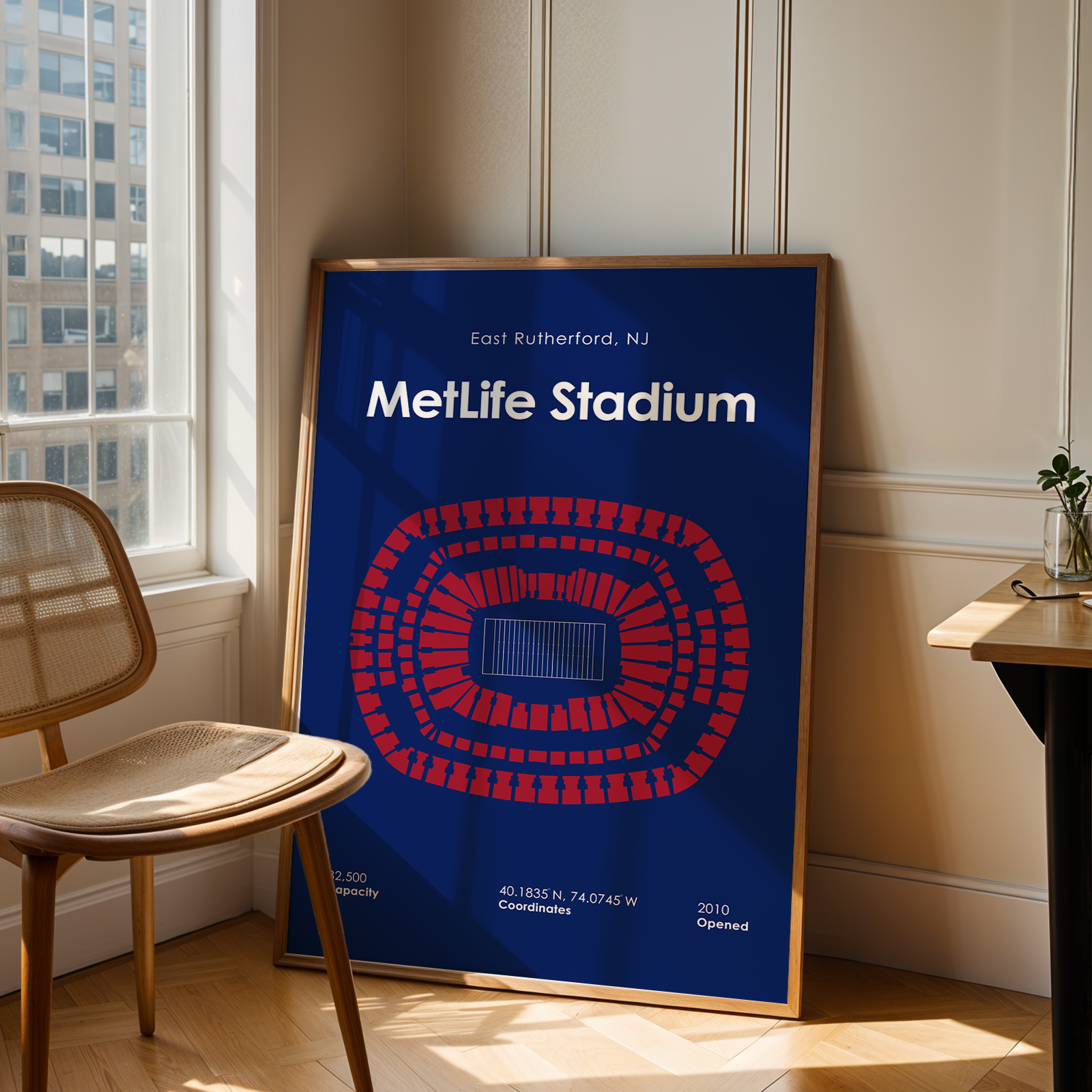 Framed poster of MetLife Stadium in a room with a chair and table.