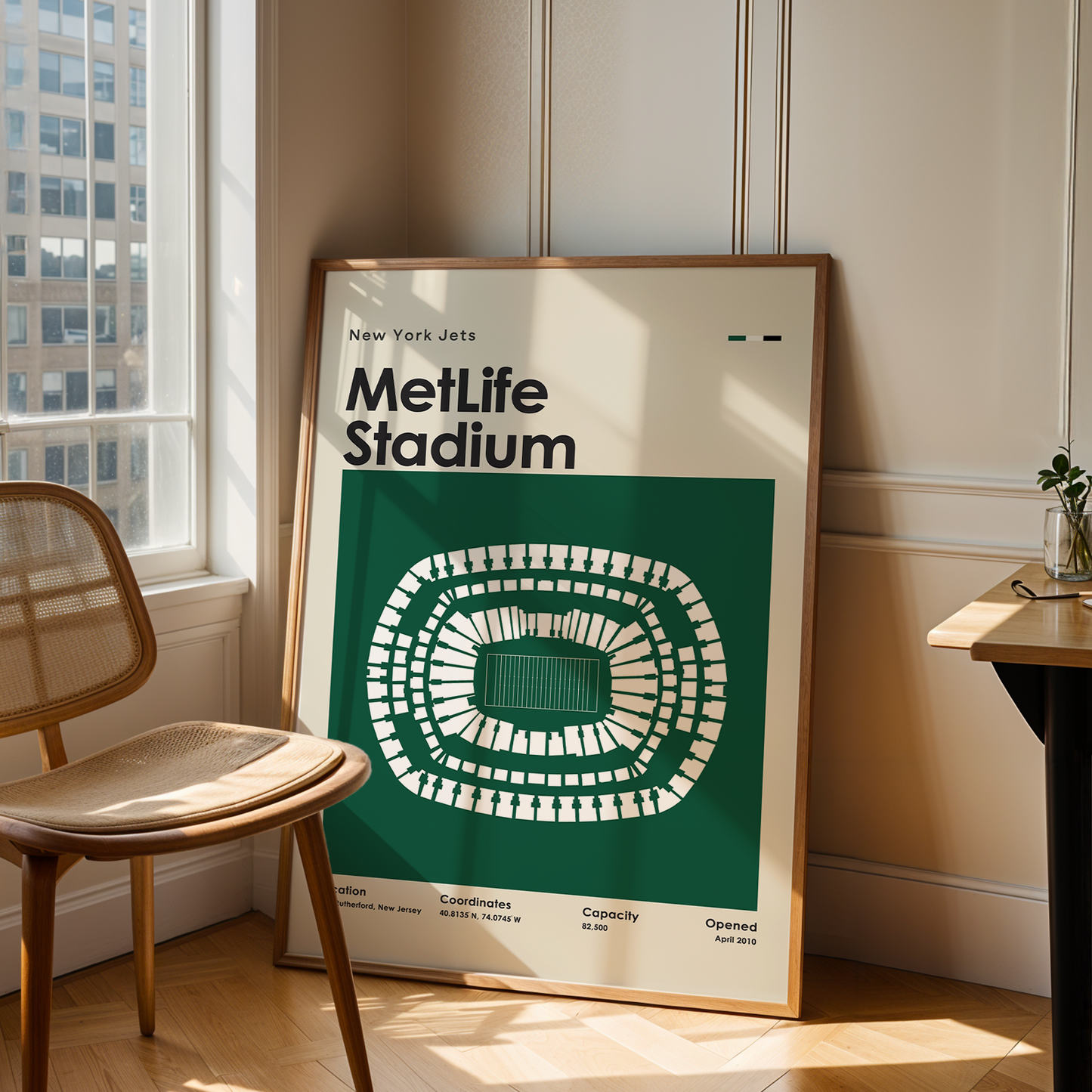 Framed poster of Metlife Stadium in a room with a chair and table.