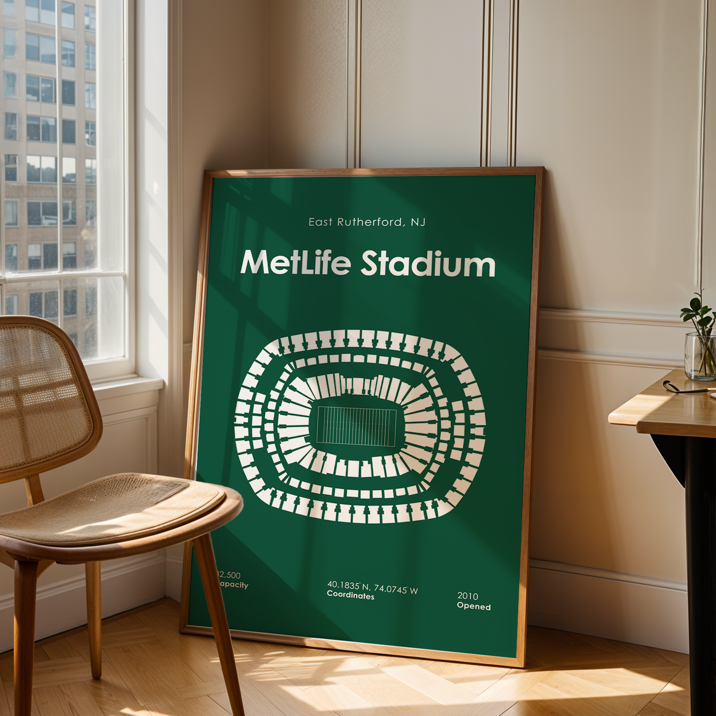 Framed poster of MetLife Stadium in a room with a chair and table.