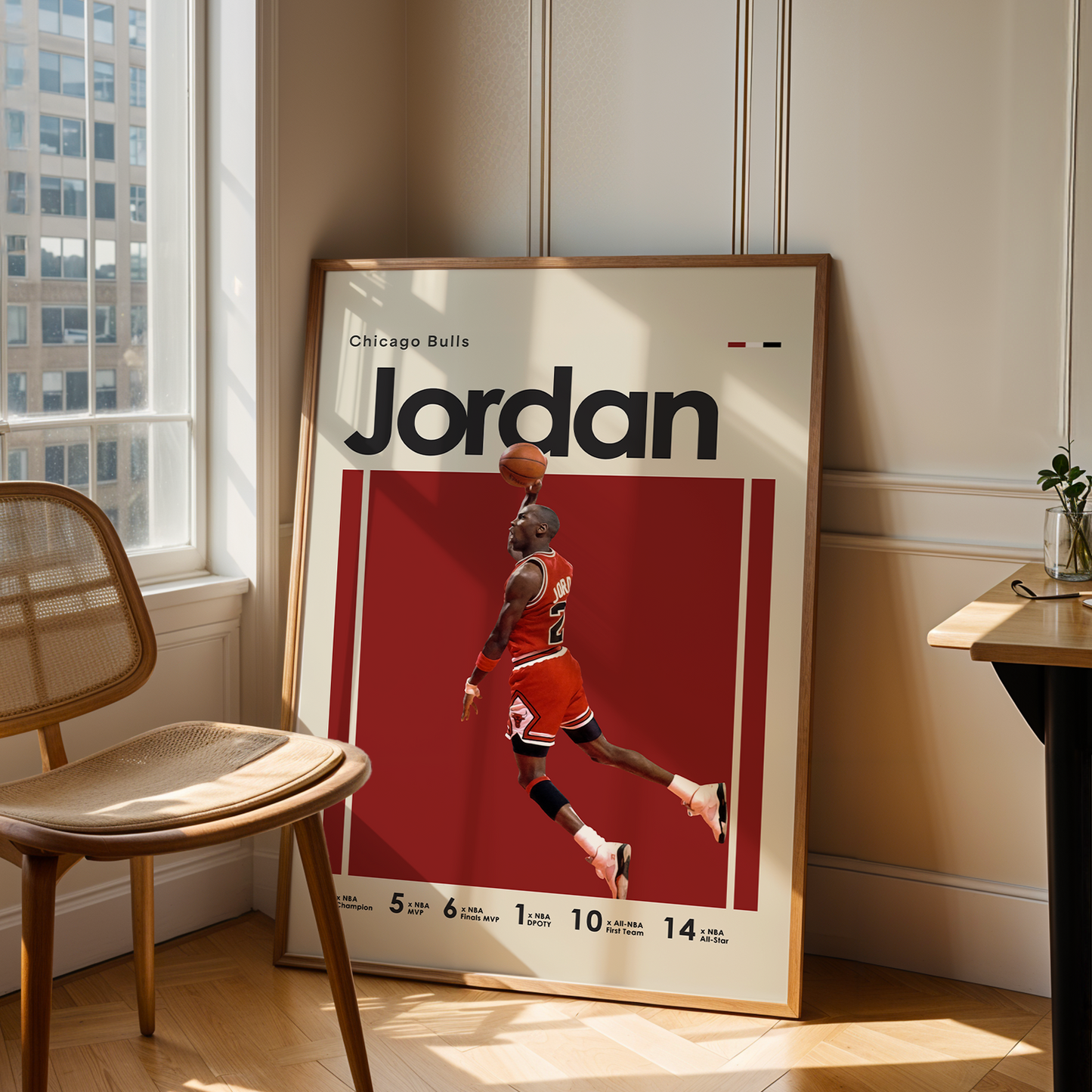 Framed poster of a basketball player named 'Jordan' leaning against a wall in a room with a chair and table.