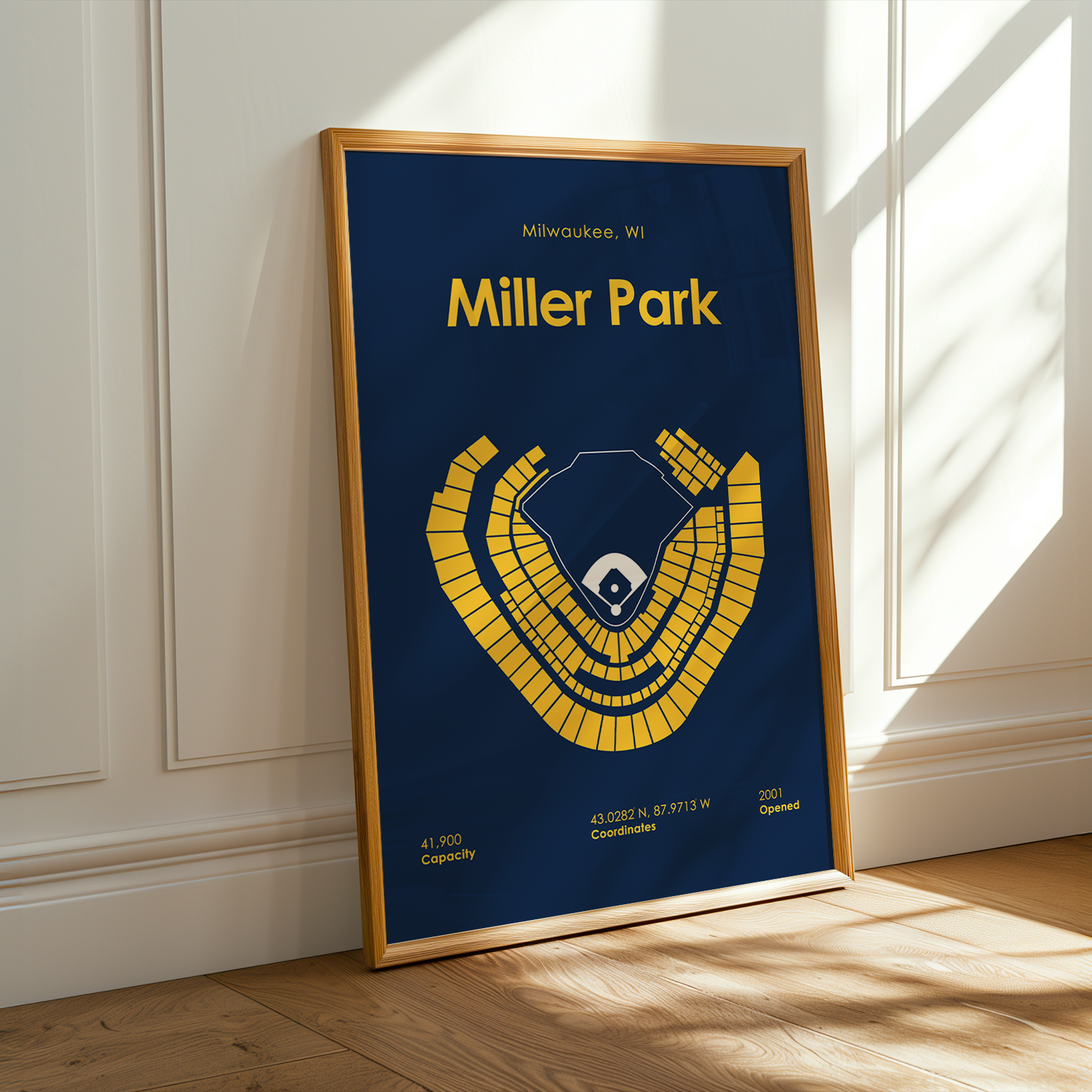 Framed poster of Miller Park with a blue background and yellow seating chart, leaning against a white wall.