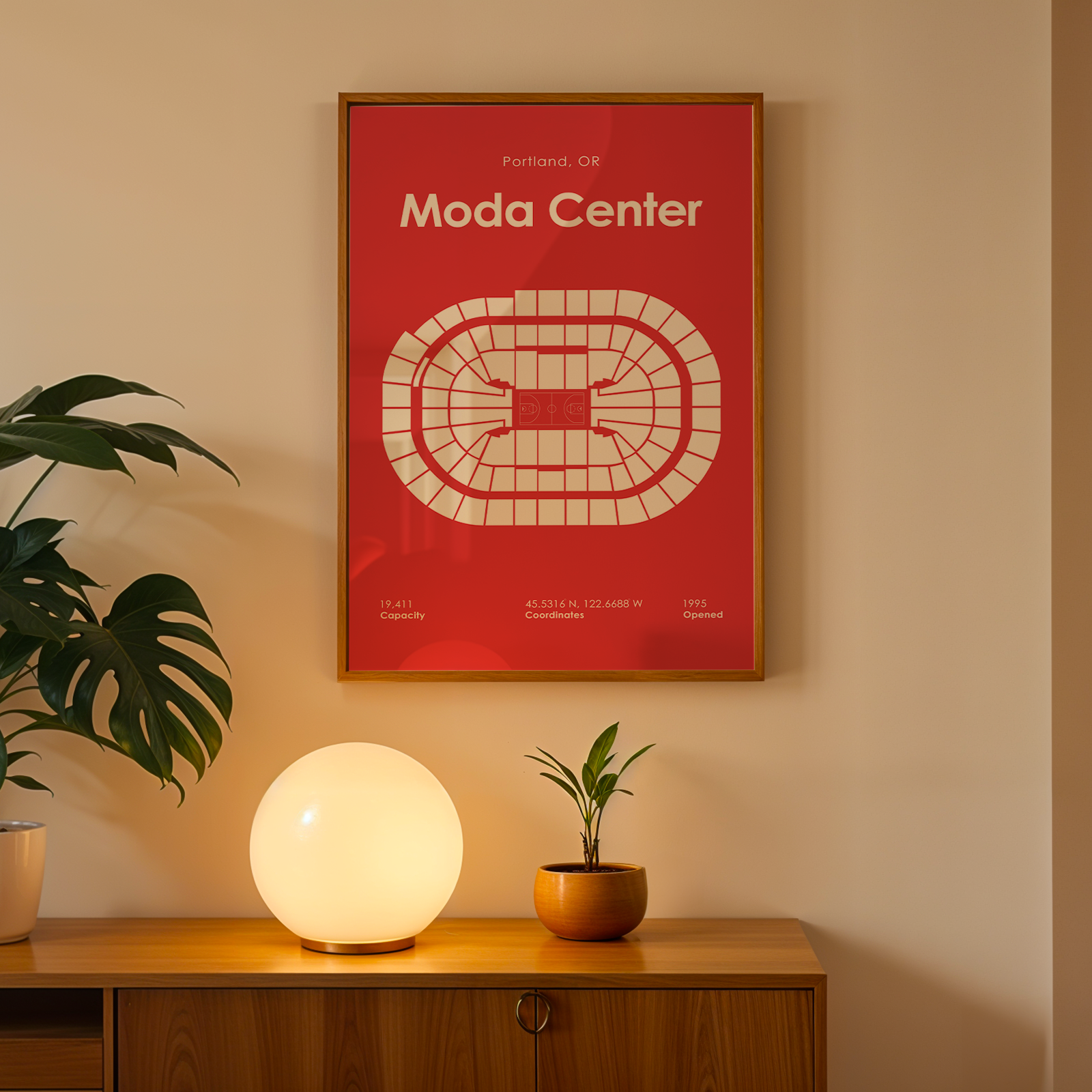 Framed poster with 'Moda Center' design on a wall above a wooden cabinet with decorative items.