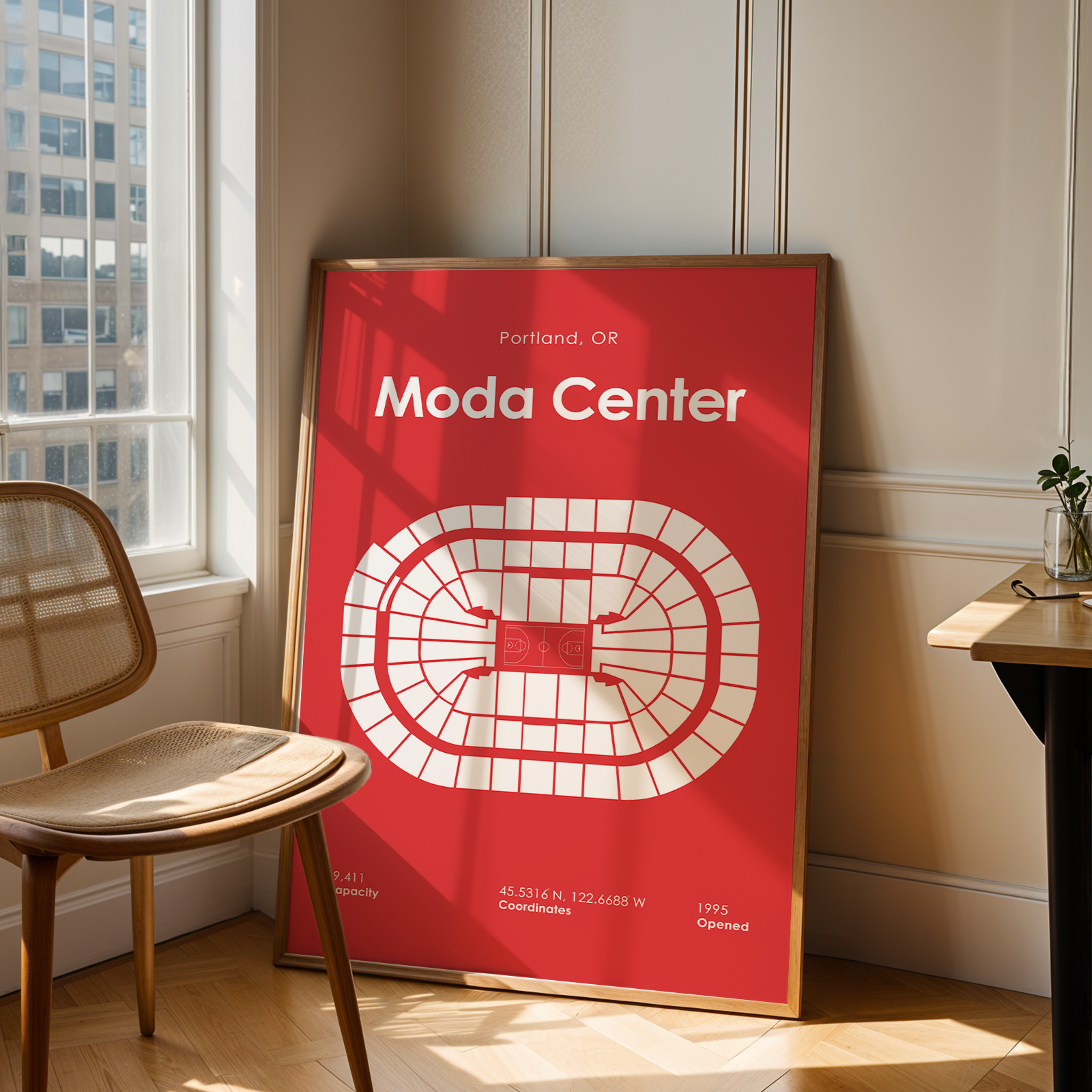 Red poster with 'Moda Center' design in a room with a chair and table.