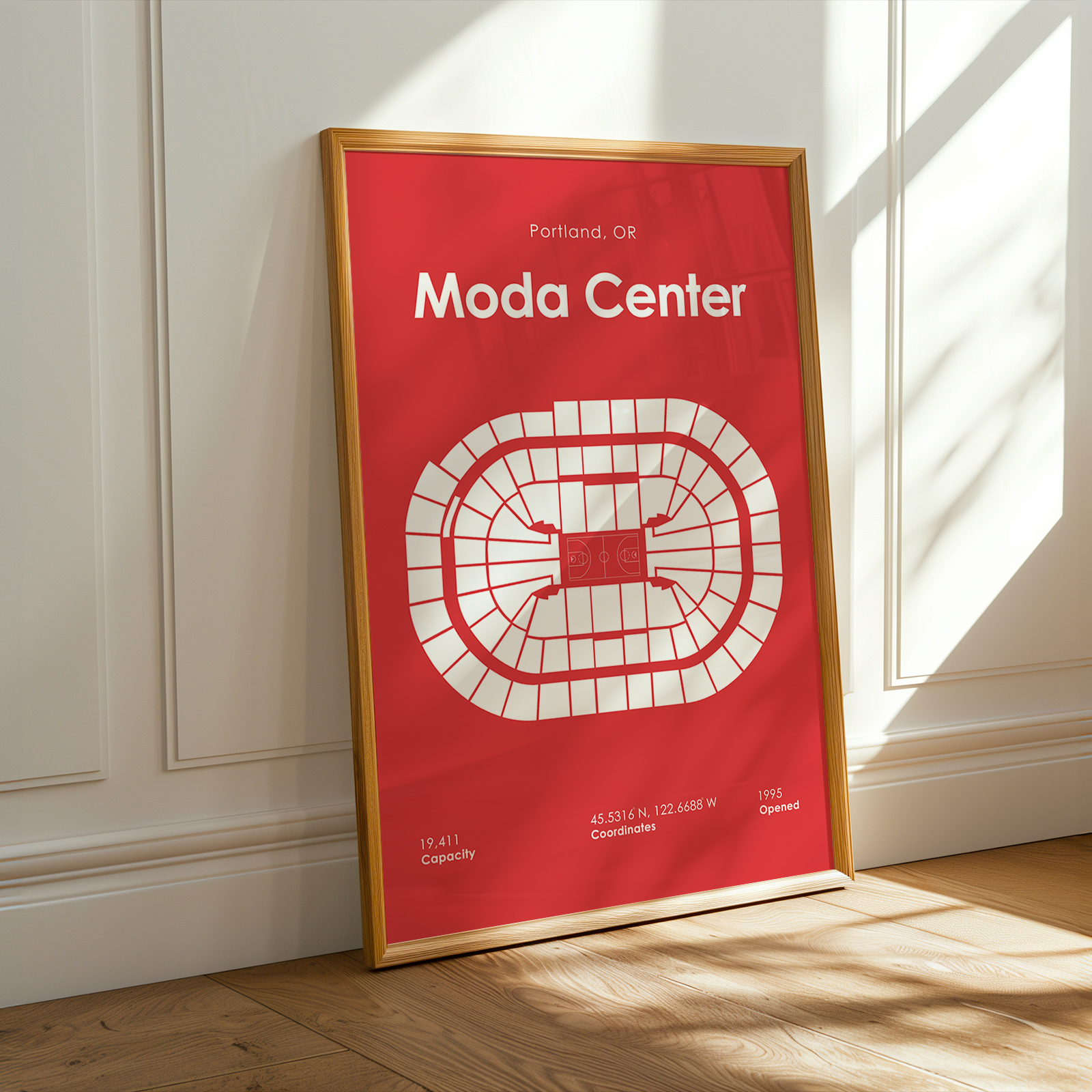 Framed poster of Moda Center layout on a wall with sunlight casting shadows.