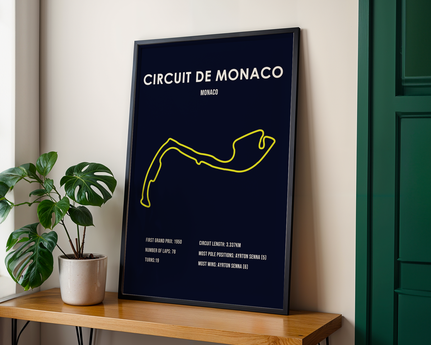 Framed poster of Circuit de Monaco on a wooden shelf with a plant in the background