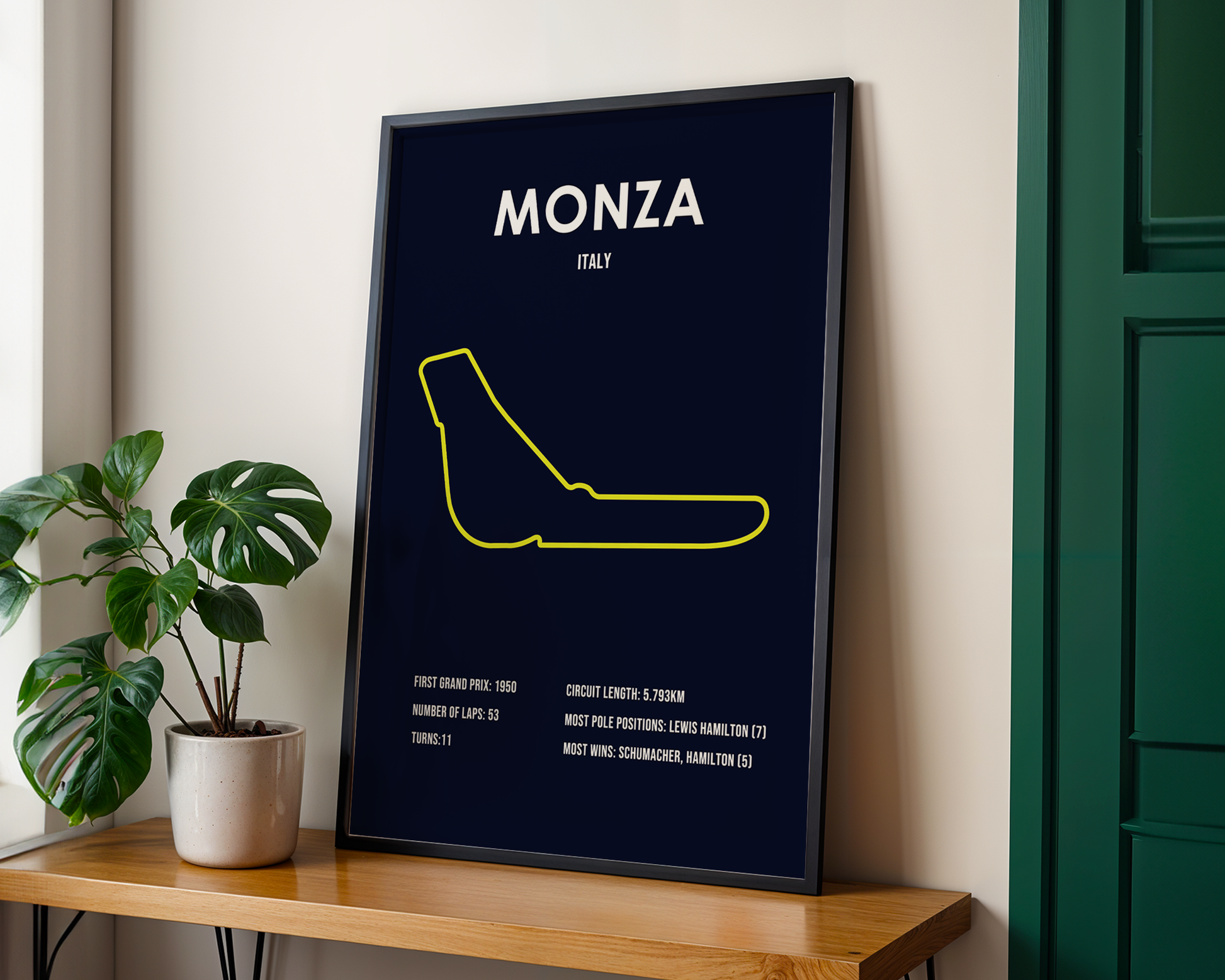 Framed poster of Monza, Italy on a wooden shelf with a plant.