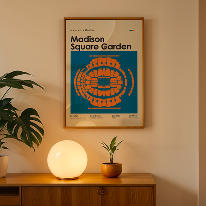 Framed Madison Square Garden poster on a wall with a plant and lamp on a wooden surface below.