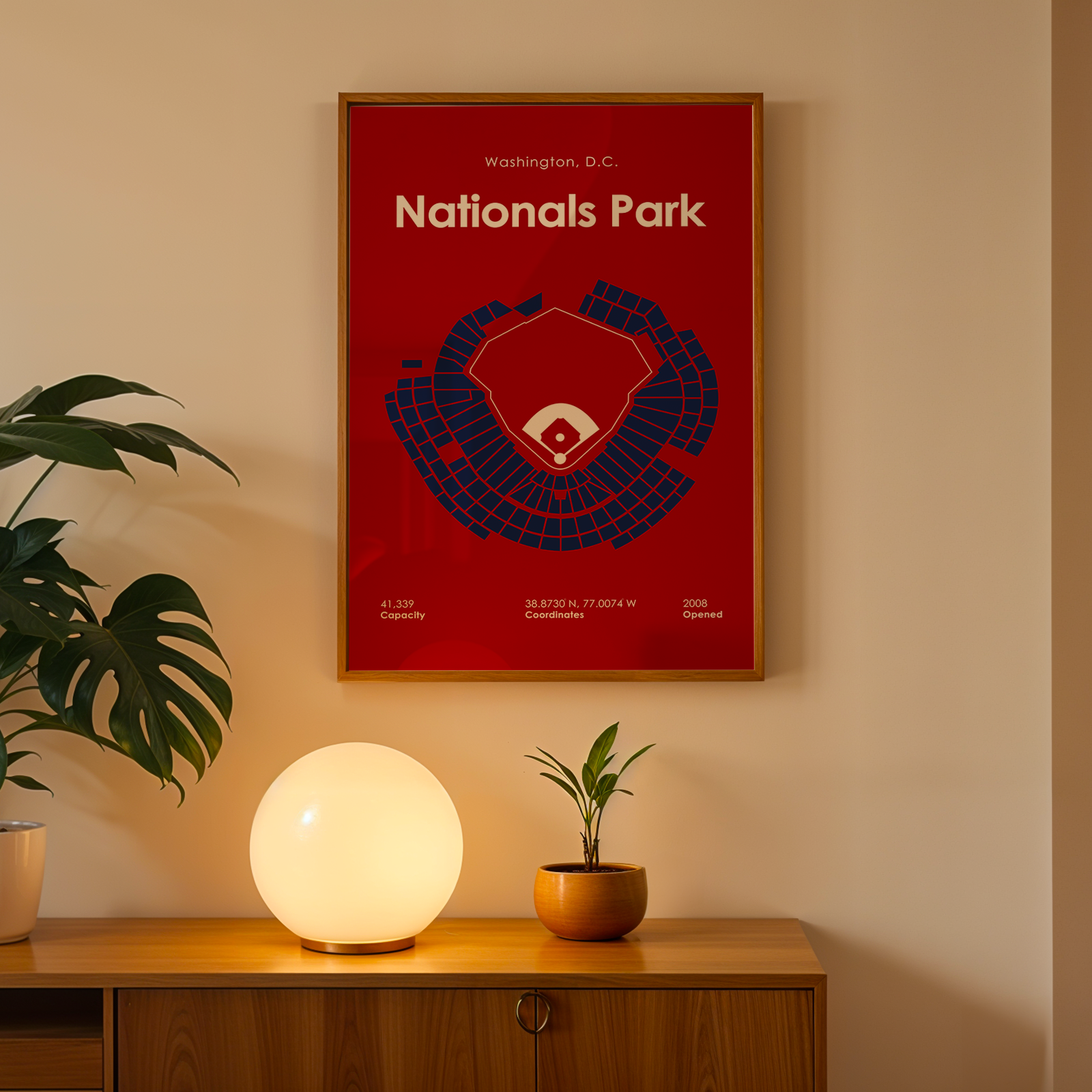 Framed poster of Nationals Park on a wall with a plant and lamp below.