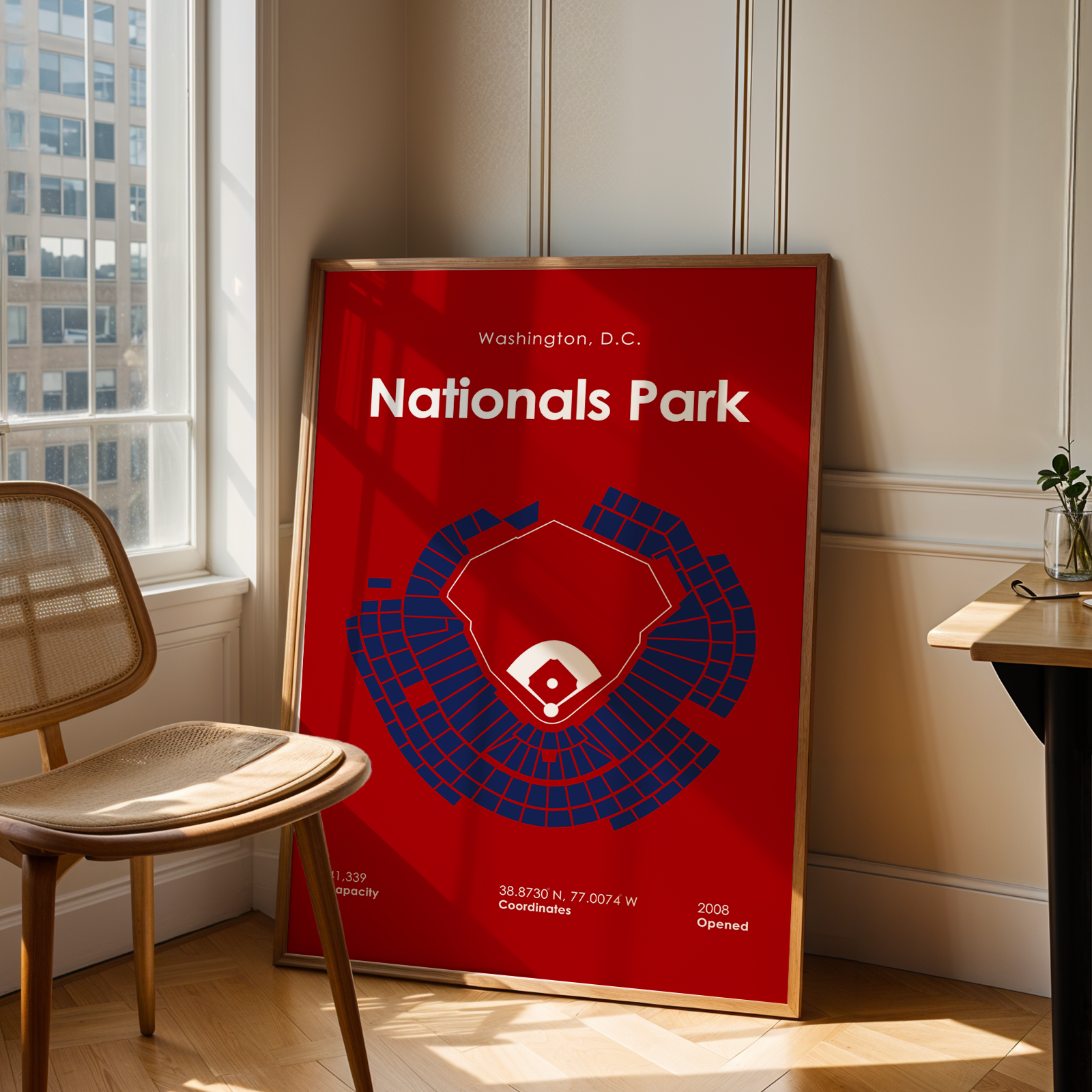 Framed poster of Nationals Park in Washington, D.C. on a wall in a room with a chair and table.