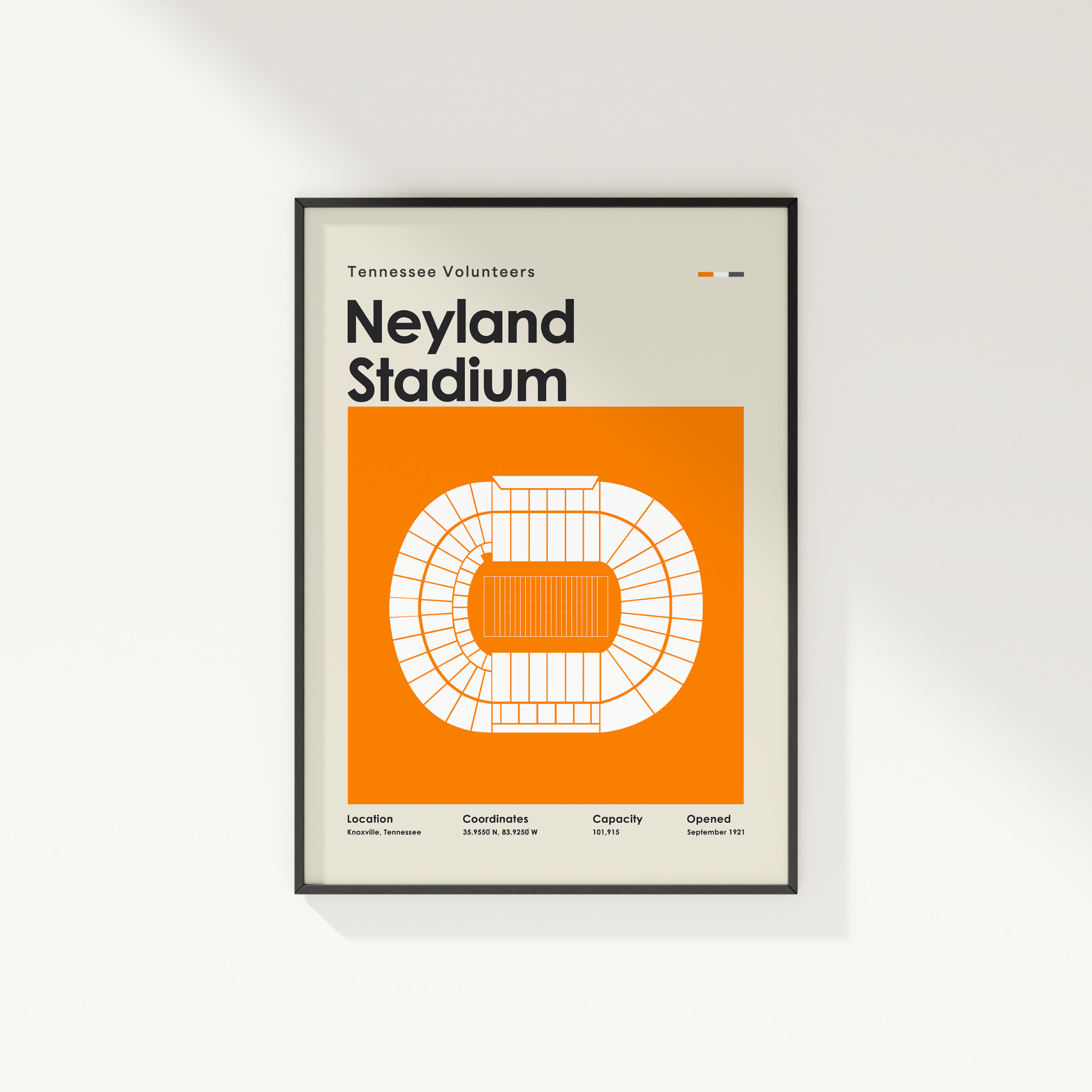 A framed Tennessee Volunteers Neyland Stadium poster with a minimalist orange and white stadium graphic, hanging on a light gray wall.