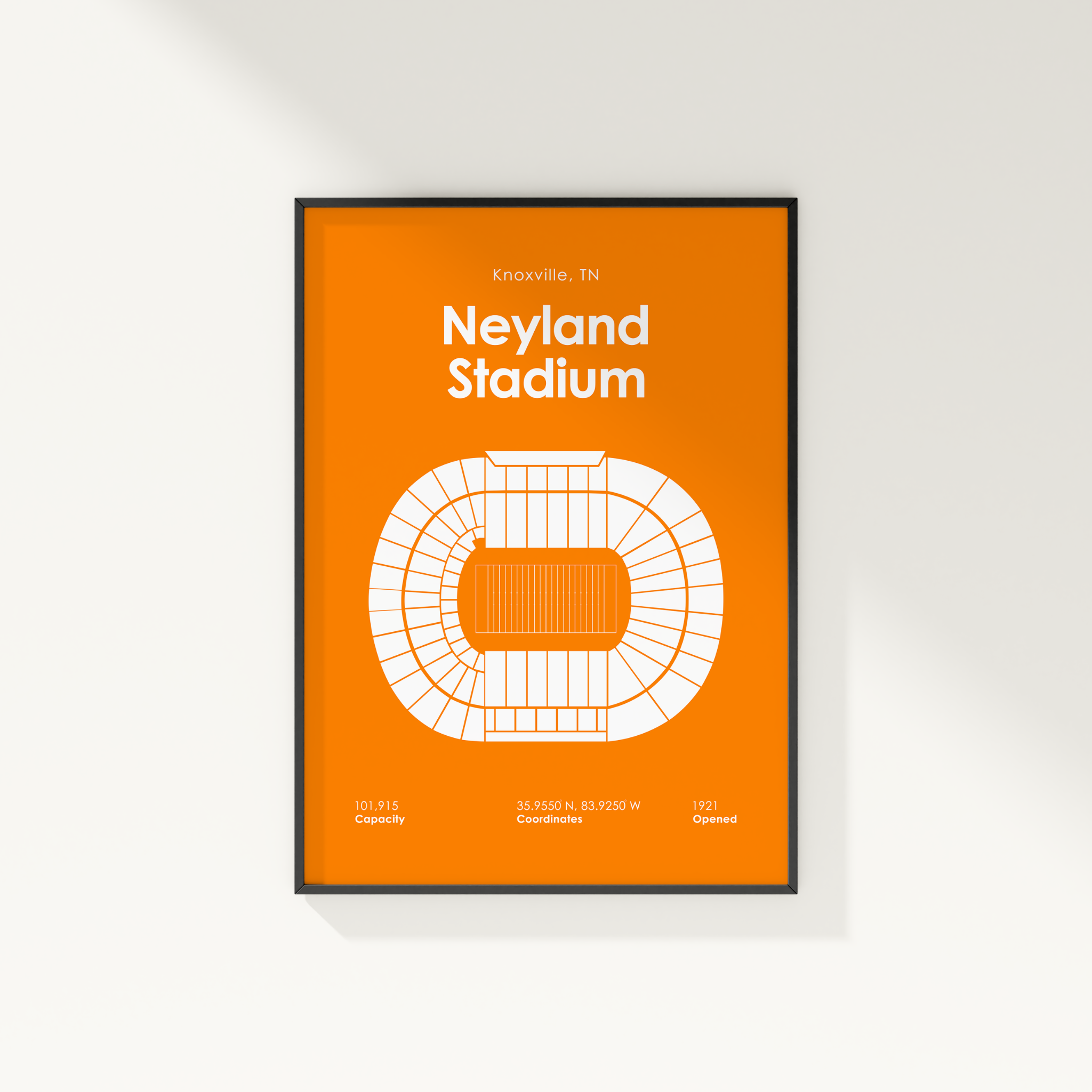 A framed minimalist stadium map poster of Neyland Stadium in Knoxville, TN, featuring a bold orange background and white line art, displayed on a clean white wall.