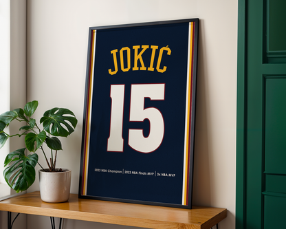 Framed sports jersey with 'JOKIC 15' on a wooden shelf with a plant.