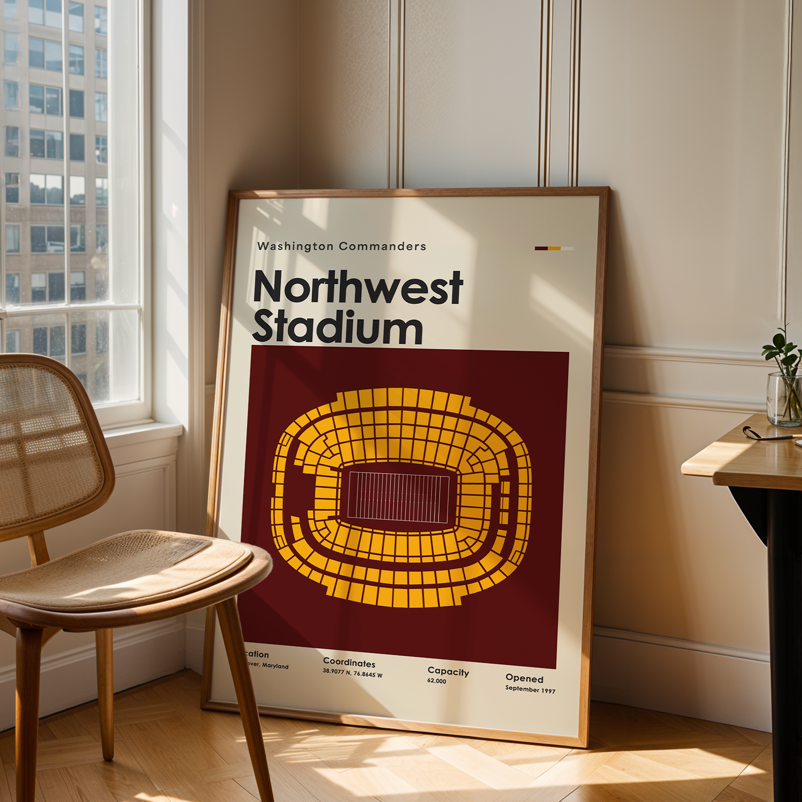 Poster of Northwest Stadium in Washington Commanders design leaning against a wall in a room with a chair and table.