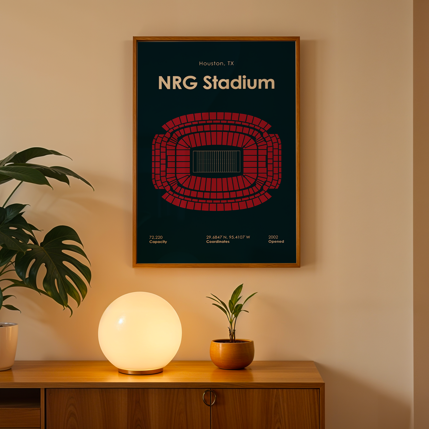 Framed poster of NRG Stadium on a wall above a wooden cabinet with decorative items.