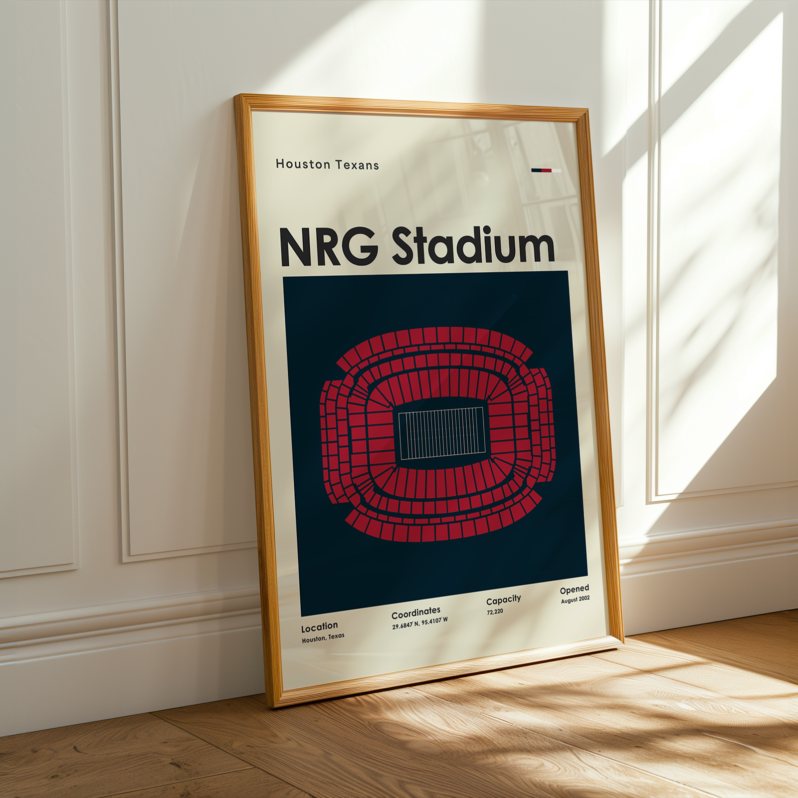 Framed poster of NRG Stadium on a wooden floor with sunlight streaming through a window.