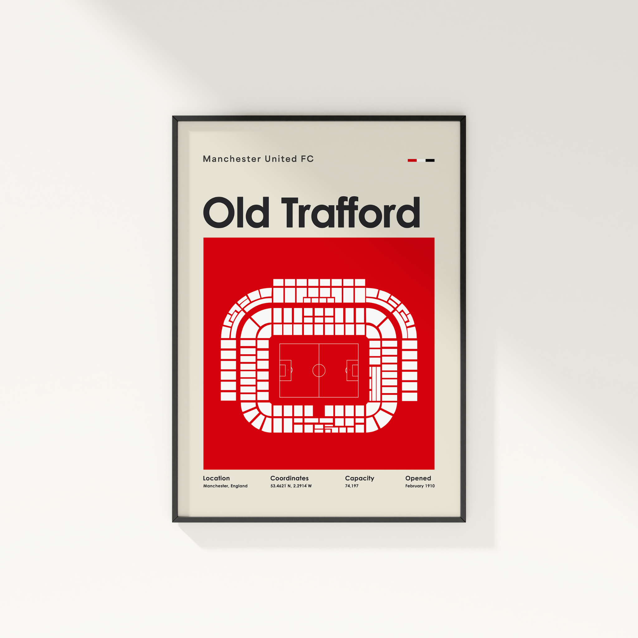 Framed poster of Old Trafford stadium layout with Manchester United FC branding on a white wall.