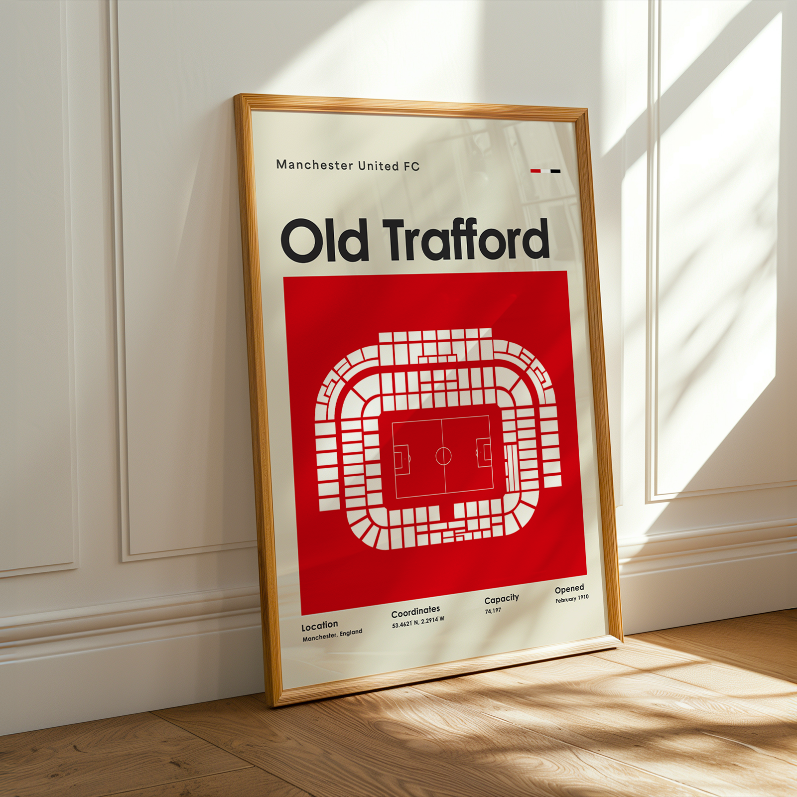 Framed poster of Old Trafford stadium layout with Manchester United FC text on a white wall.