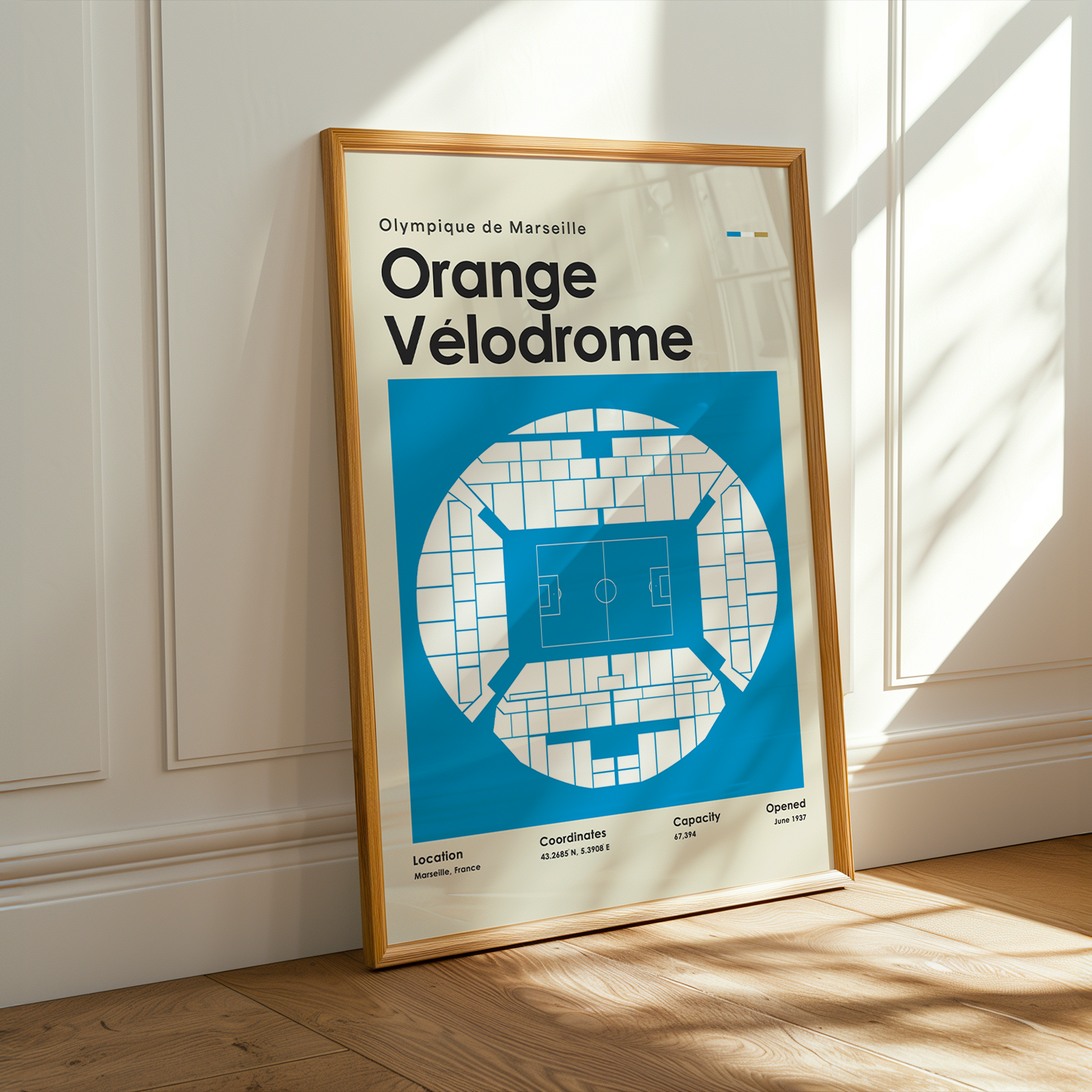 Framed poster of Orange Velodrome with blue and white design, placed on a wooden floor.