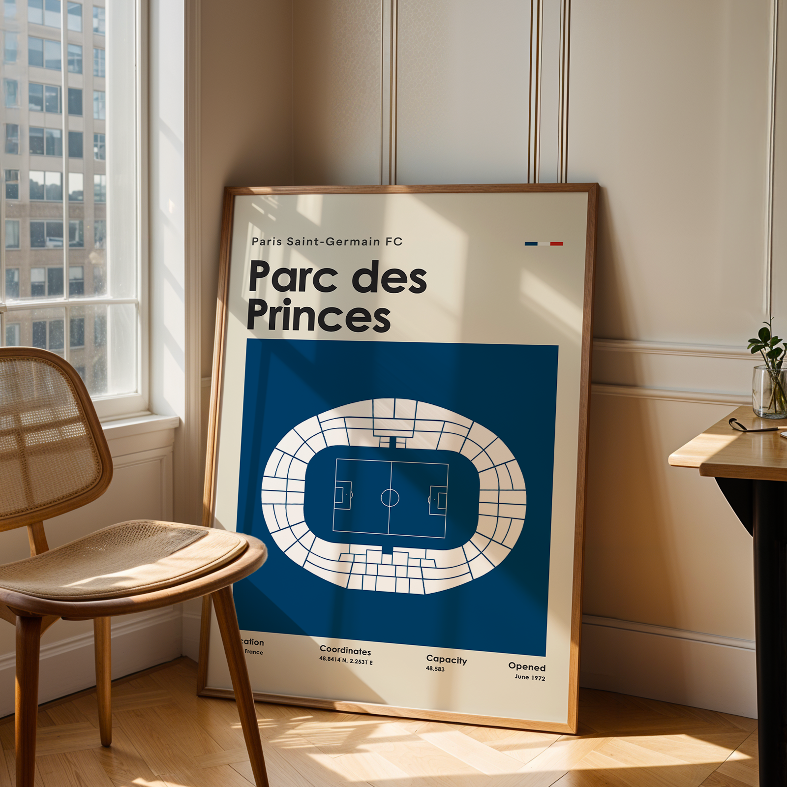Framed poster of Parc des Princes stadium layout in a room with a window and chair.