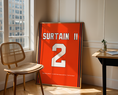Framed sports jersey with 'Surtain II' and number '2' in a room with a window and chair.
