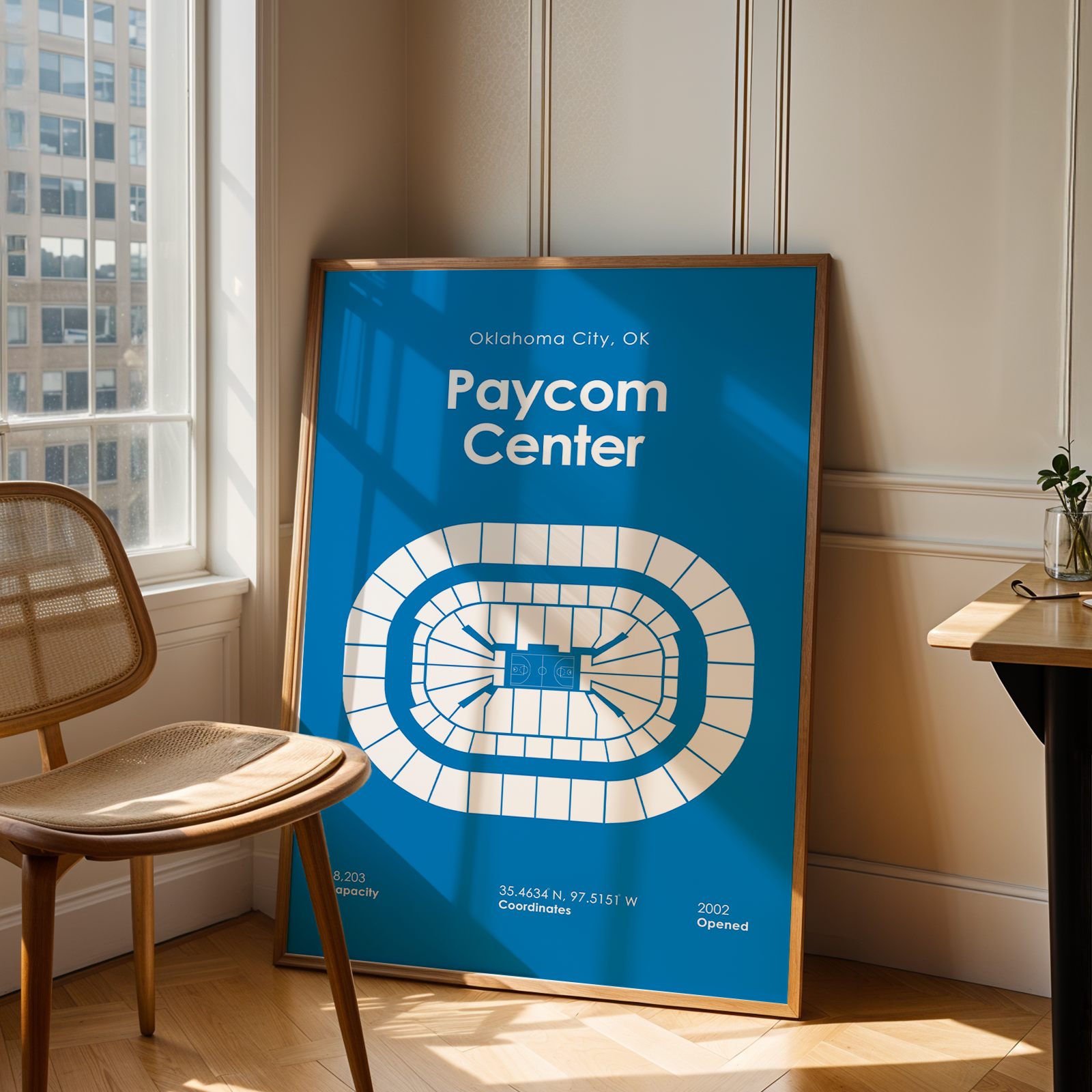 Poster of Paycom Center in Oklahoma City, OK, leaning against a wall in a room with a chair and table.