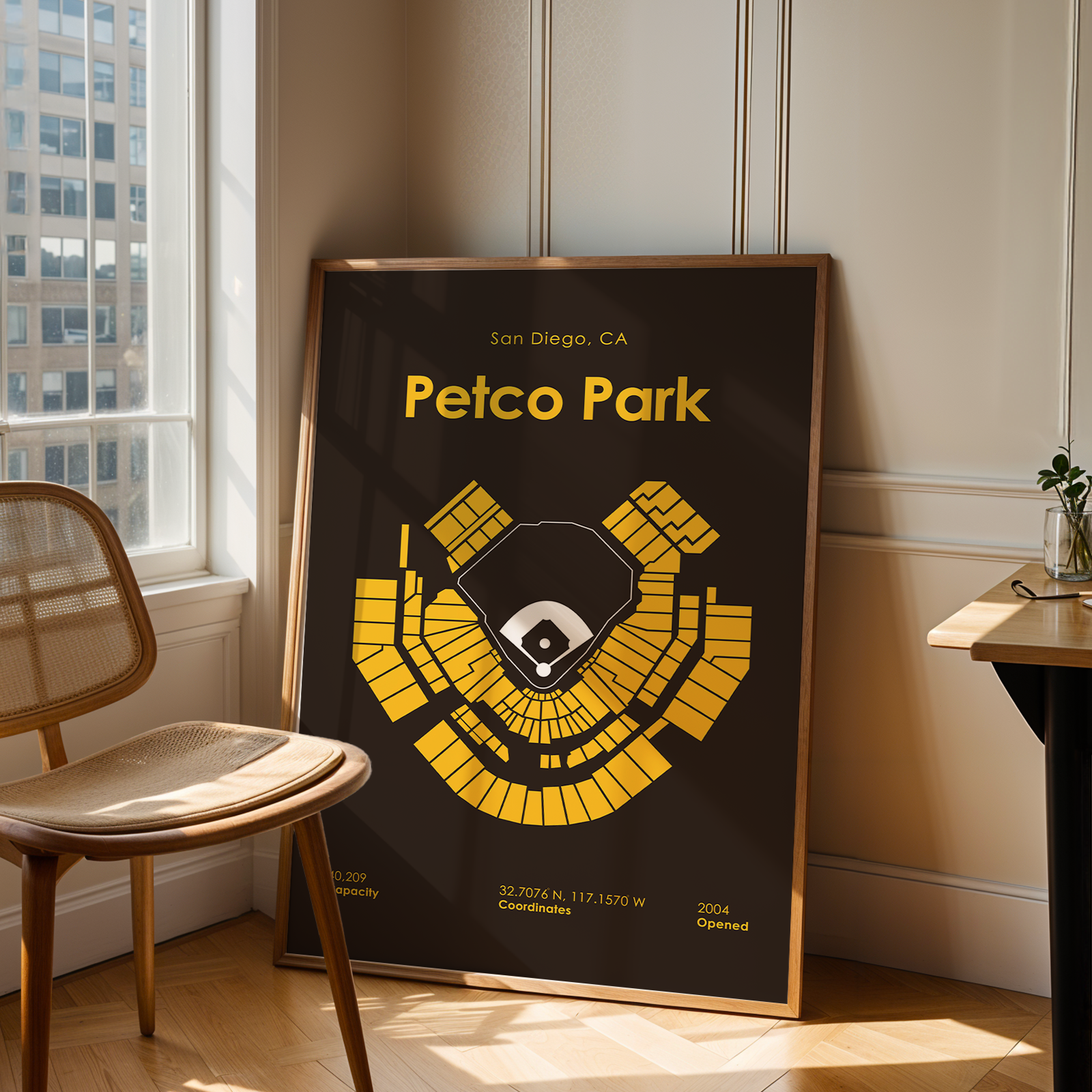 Framed poster of Petco Park layout in a room with a chair and window.