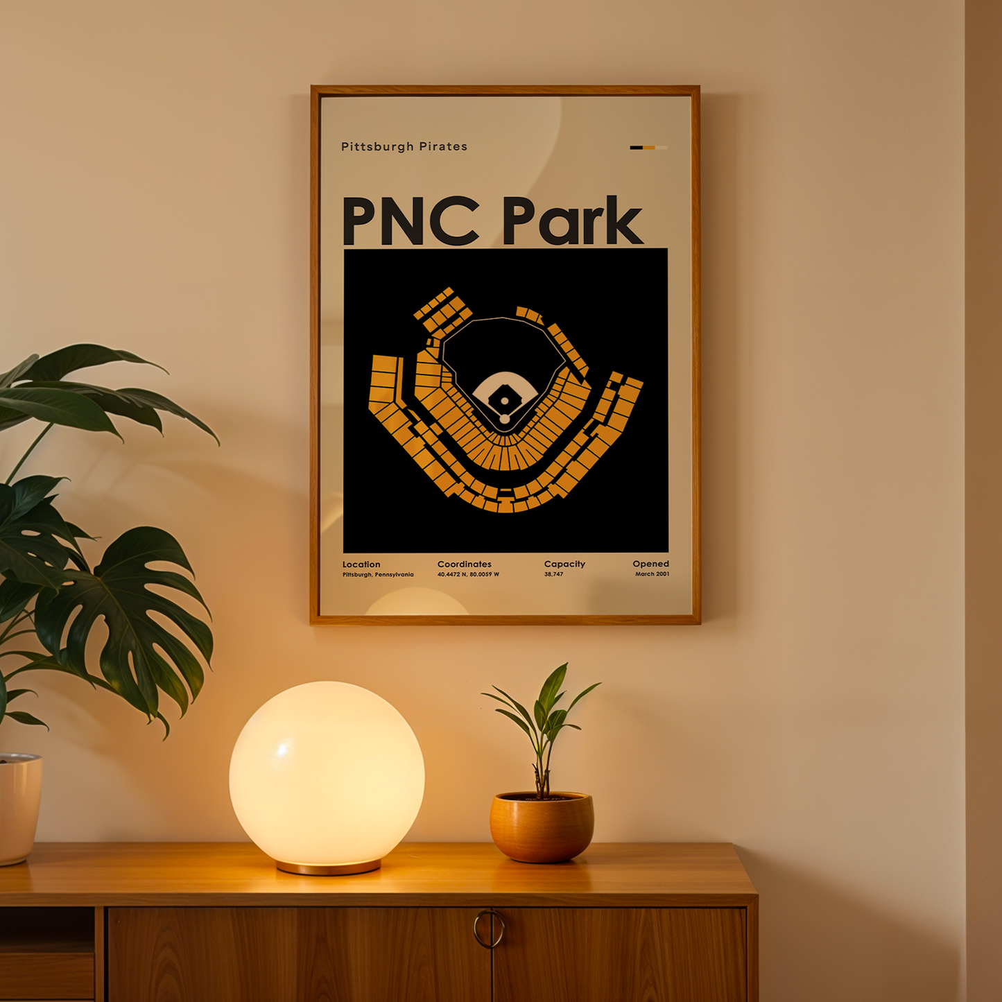 Framed poster of PNC Park on a wall above a wooden cabinet with decorative items.
