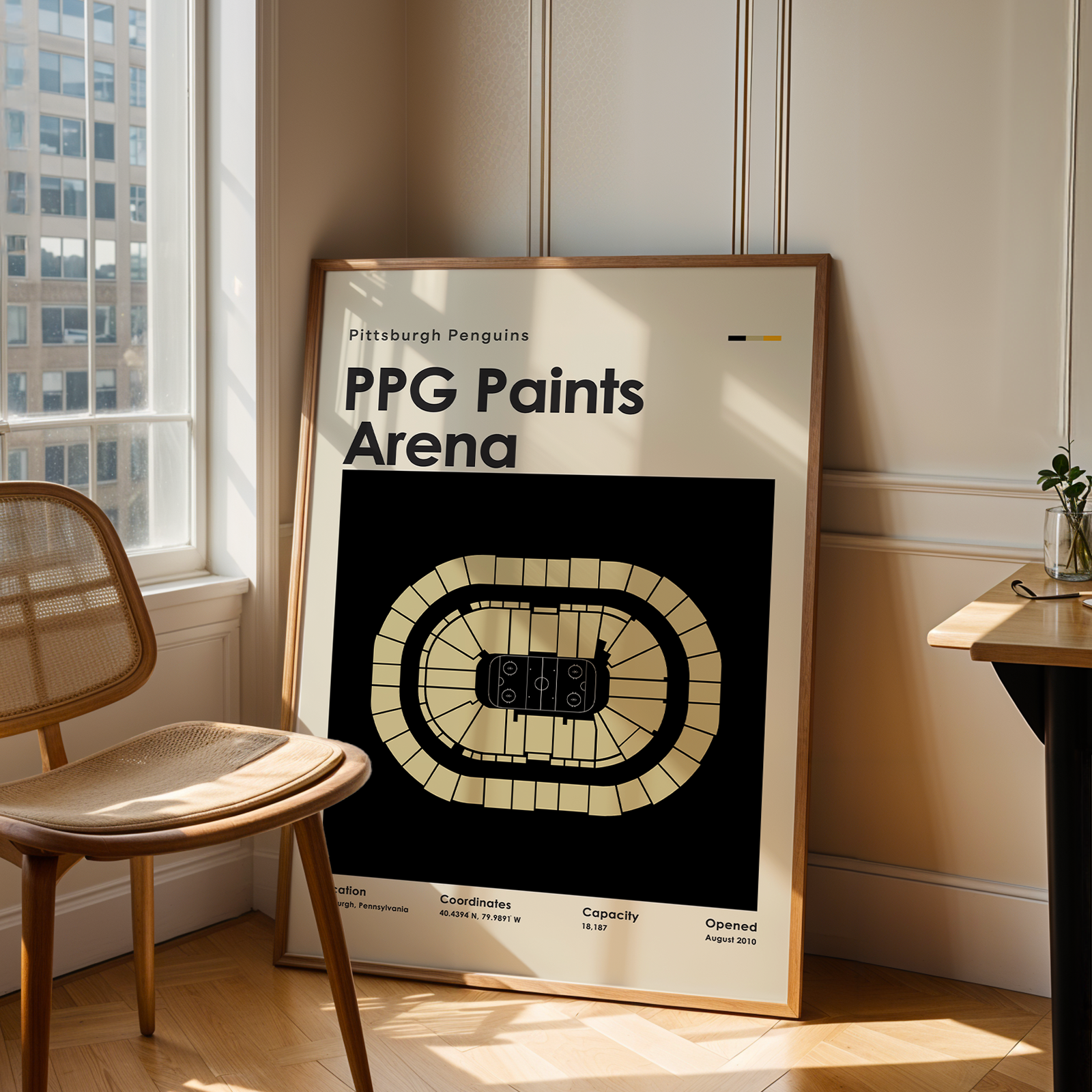 Framed poster of PPG Paints Arena in a room with a chair and table.