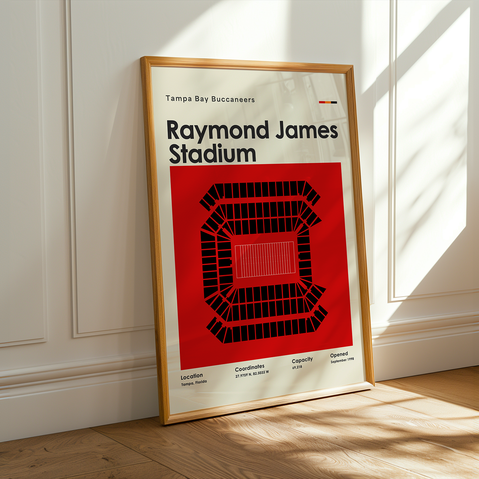 Framed poster of Raymond James Stadium on a wall with sunlight casting shadows.
