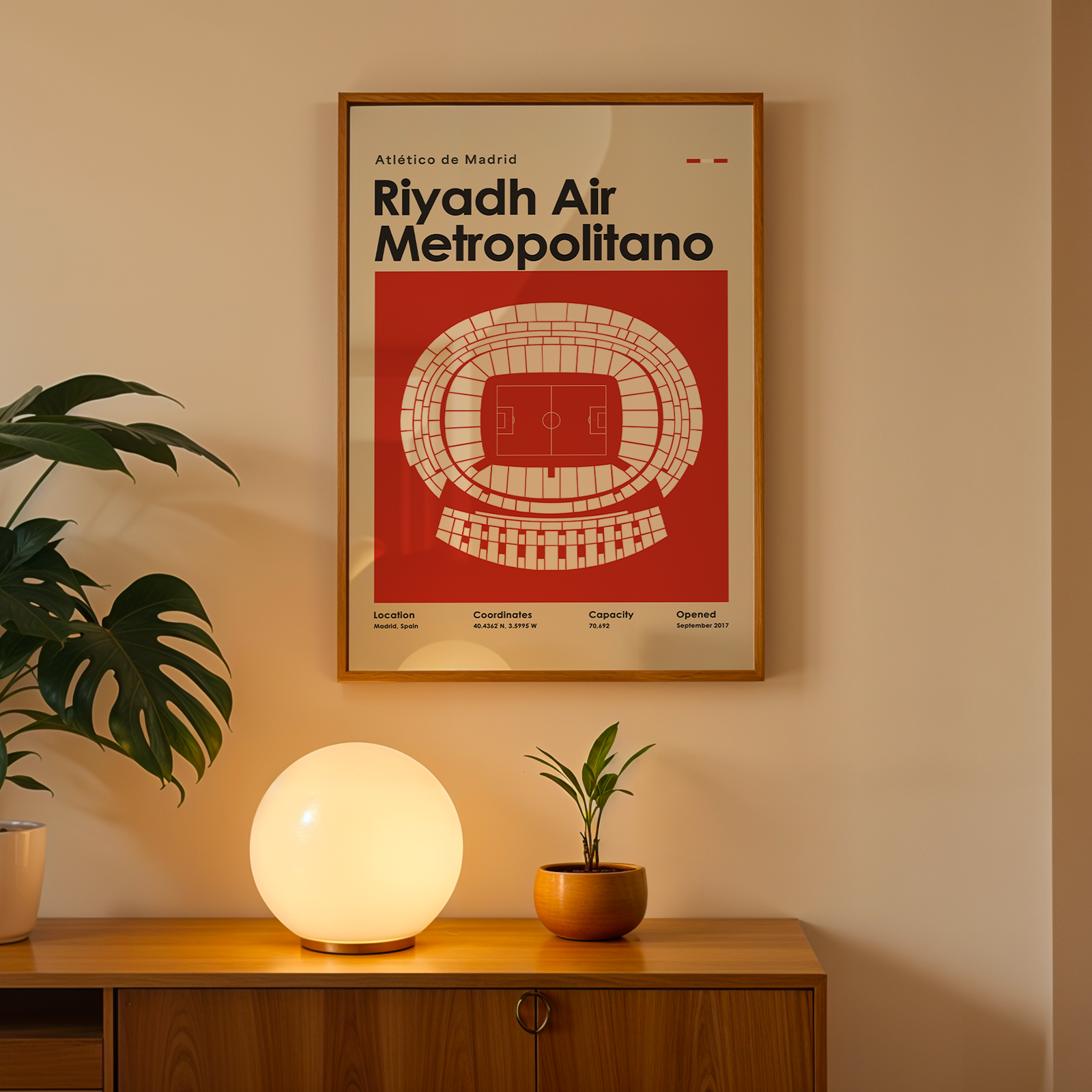 Framed poster of Riyadh Air Metropolitano on a wall above a wooden cabinet with decorative items.