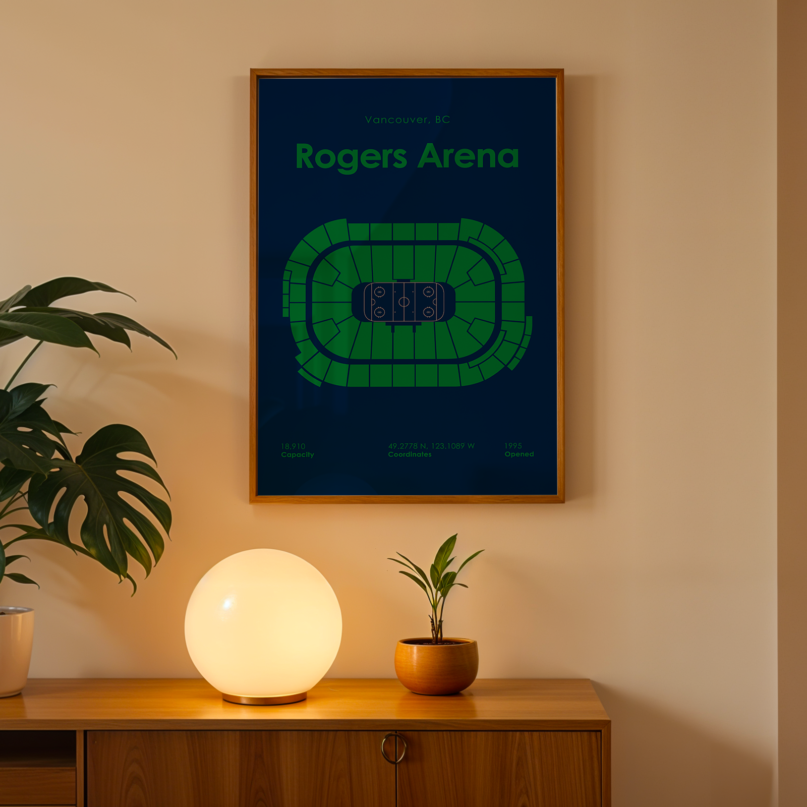 Framed poster of Rogers Arena on a wall with a lamp and plant below.