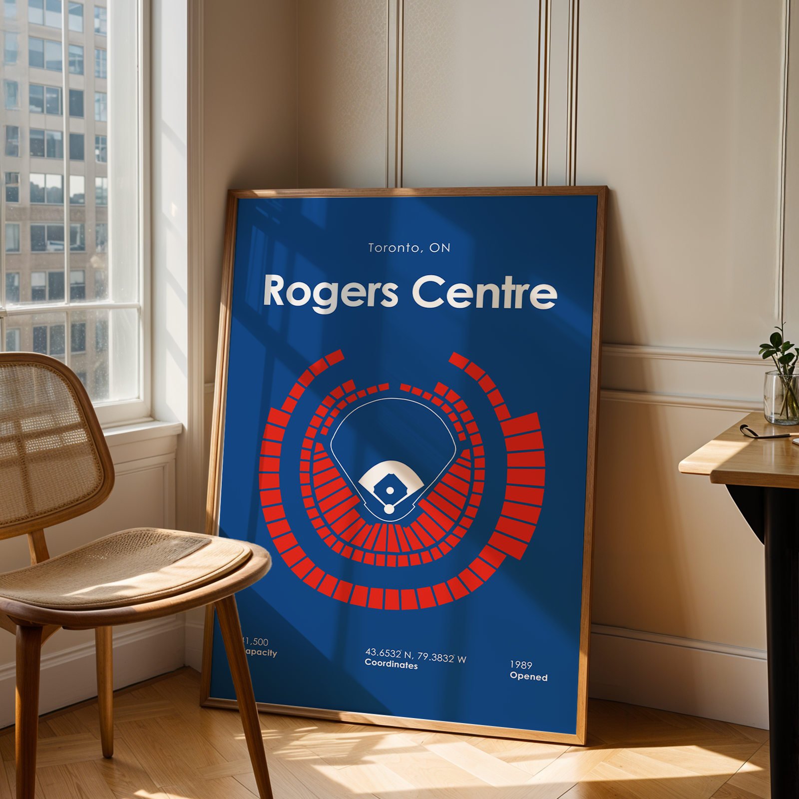 Framed poster of Rogers Centre in Toronto, ON on a wall in a room with a window and chair.