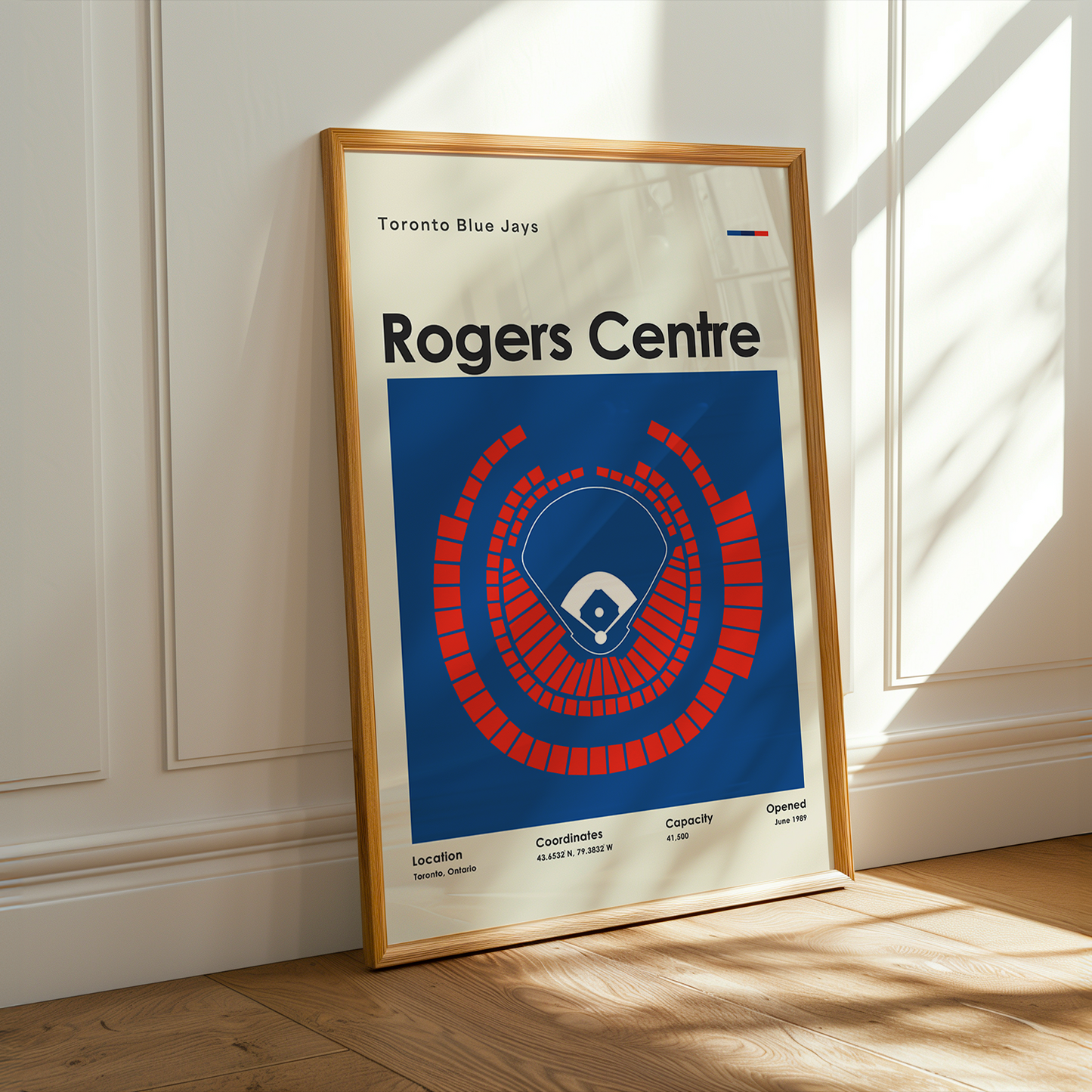 Framed poster of the Rogers Centre in Toronto on a wooden floor with sunlight streaming in.