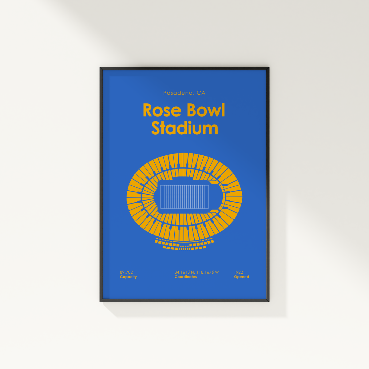 A framed poster of Rose Bowl Stadium in Pasadena, CA, featuring a blue background with yellow text and a yellow stadium layout diagram, shown hanging on a white wall.