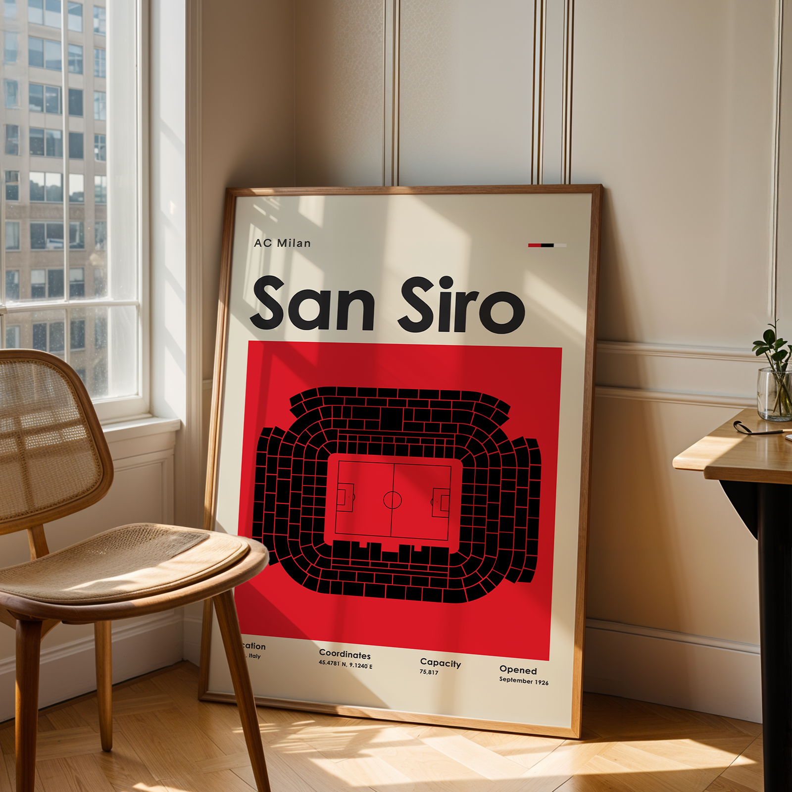 Framed poster of San Siro stadium layout in a room with a chair and window.