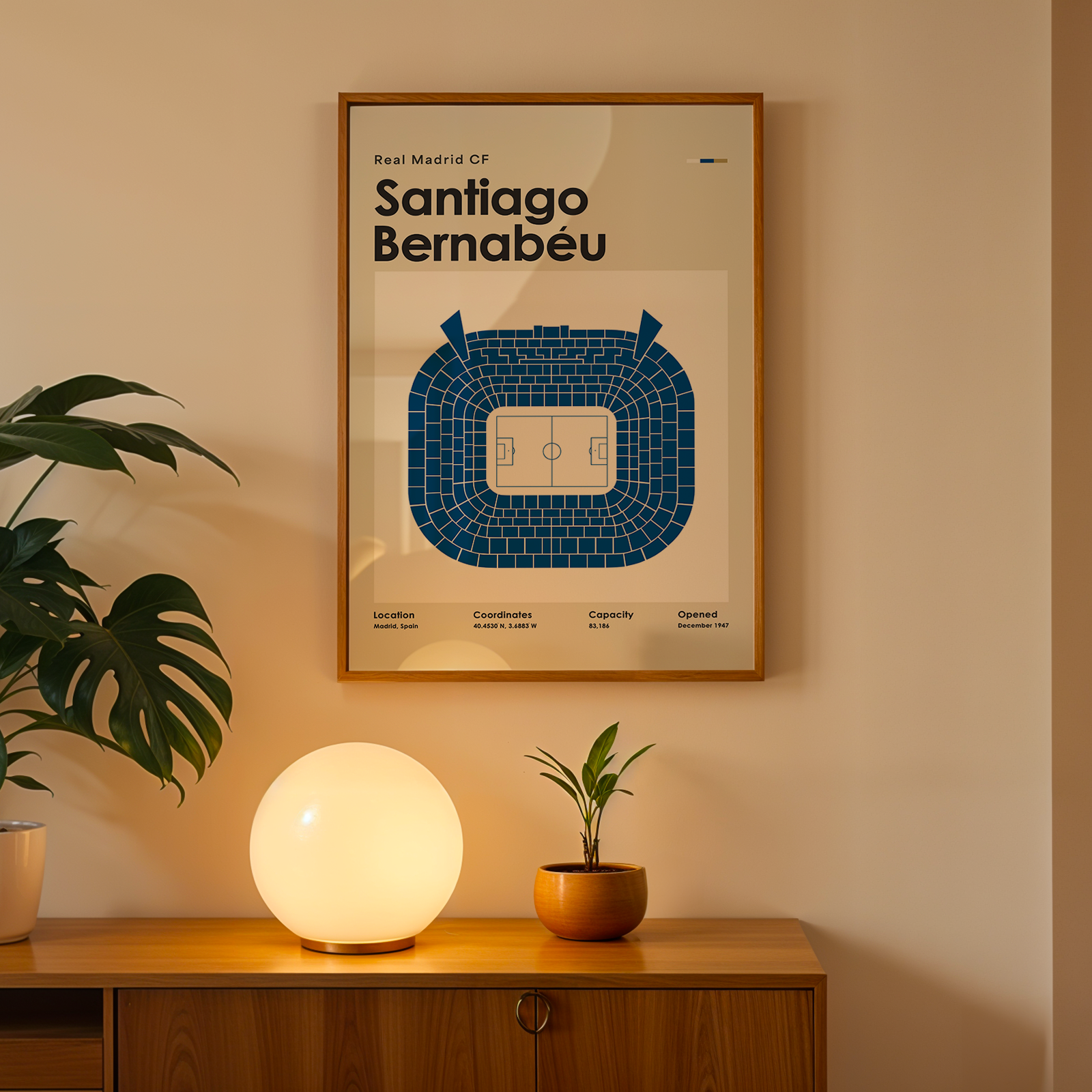 Framed Santiago Bernabéu stadium map on a wall above a wooden cabinet with decorative items.
