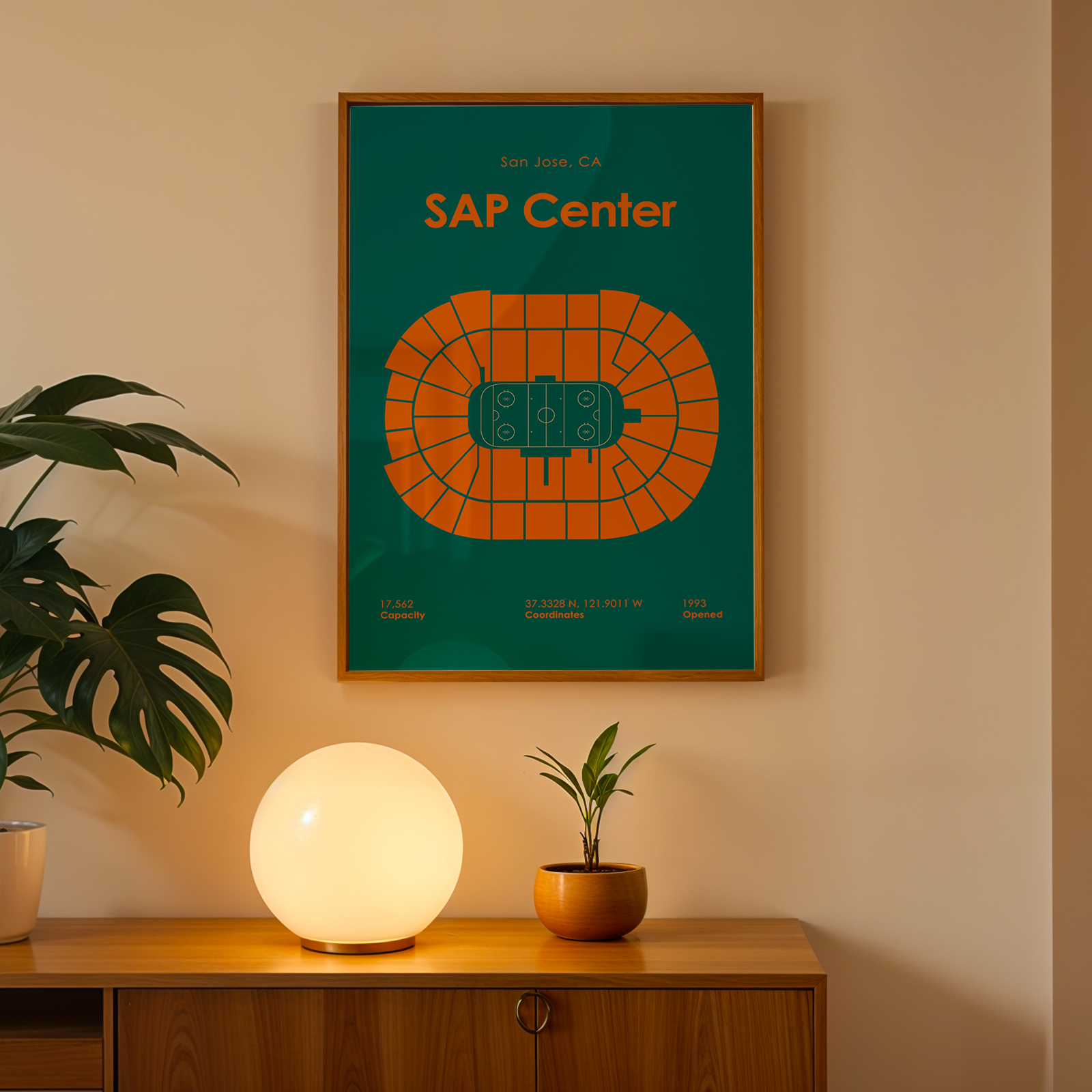 Framed SAP Center map poster on a wall with a lamp and plant below.