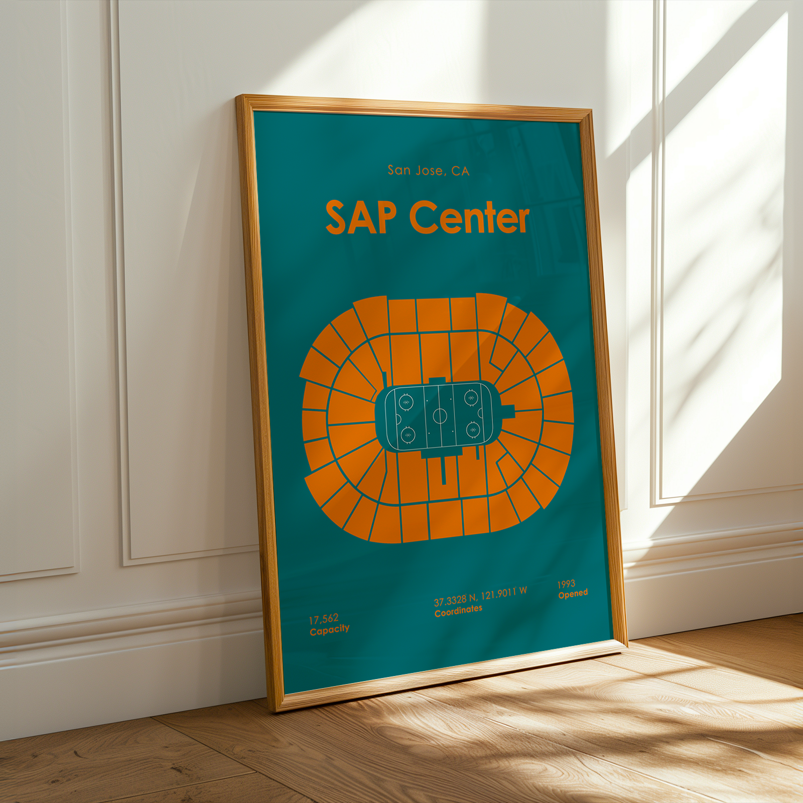 Framed poster of SAP Center with a blue background and orange seating chart, leaning against a white wall.