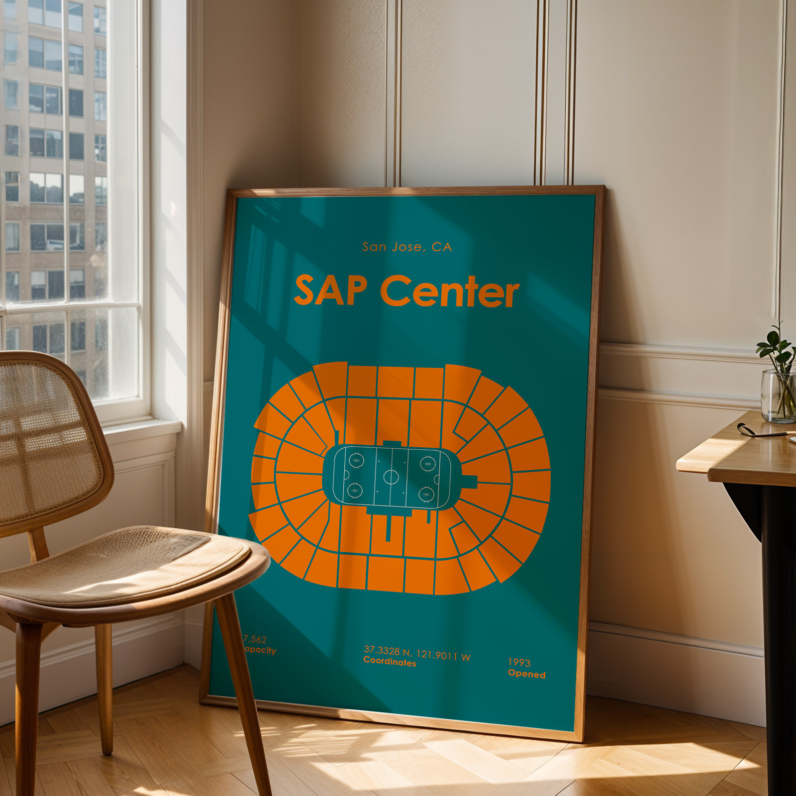 Framed poster of SAP Center in San Jose, CA on a wall next to a chair.
