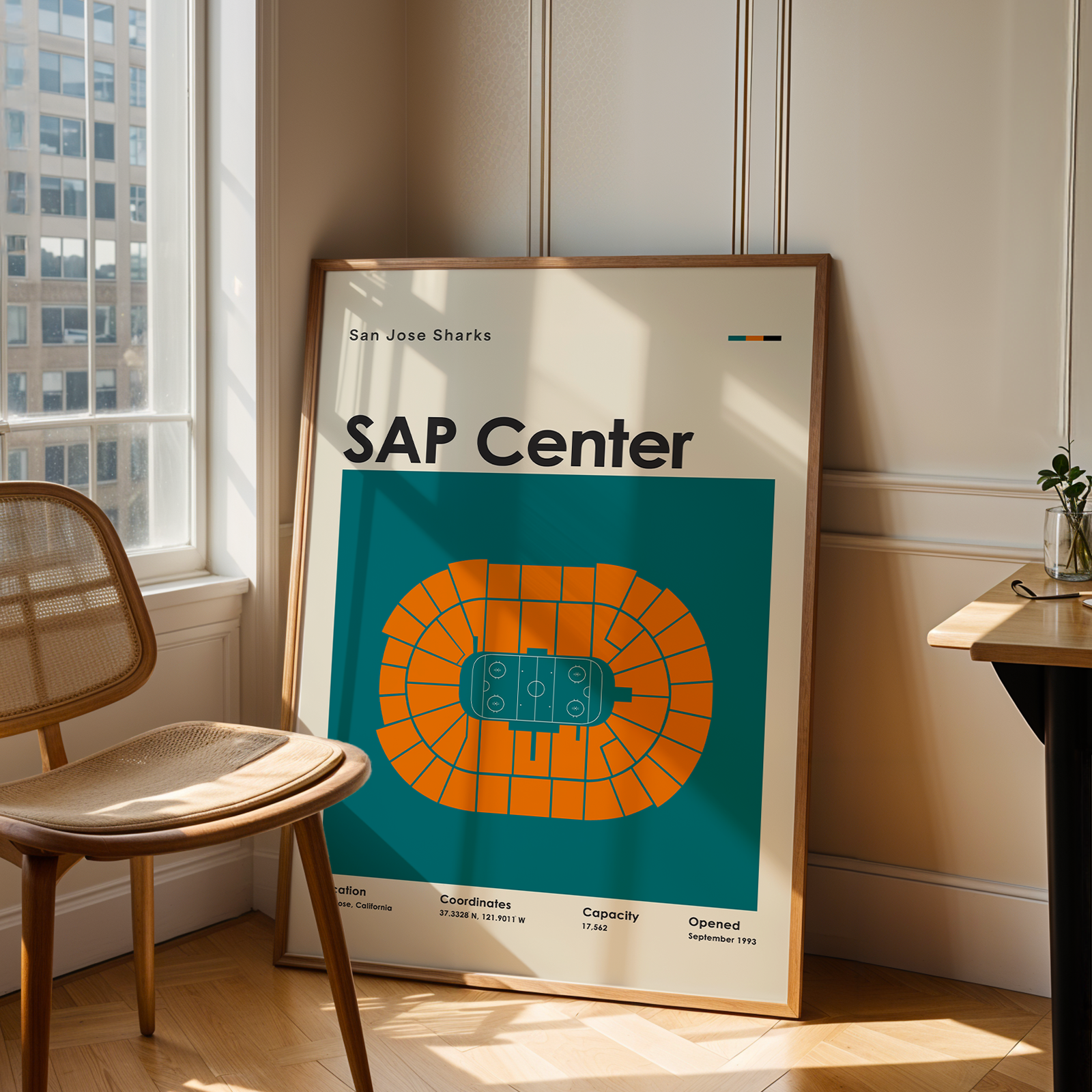 Framed poster of SAP Center in a room with a chair and table.