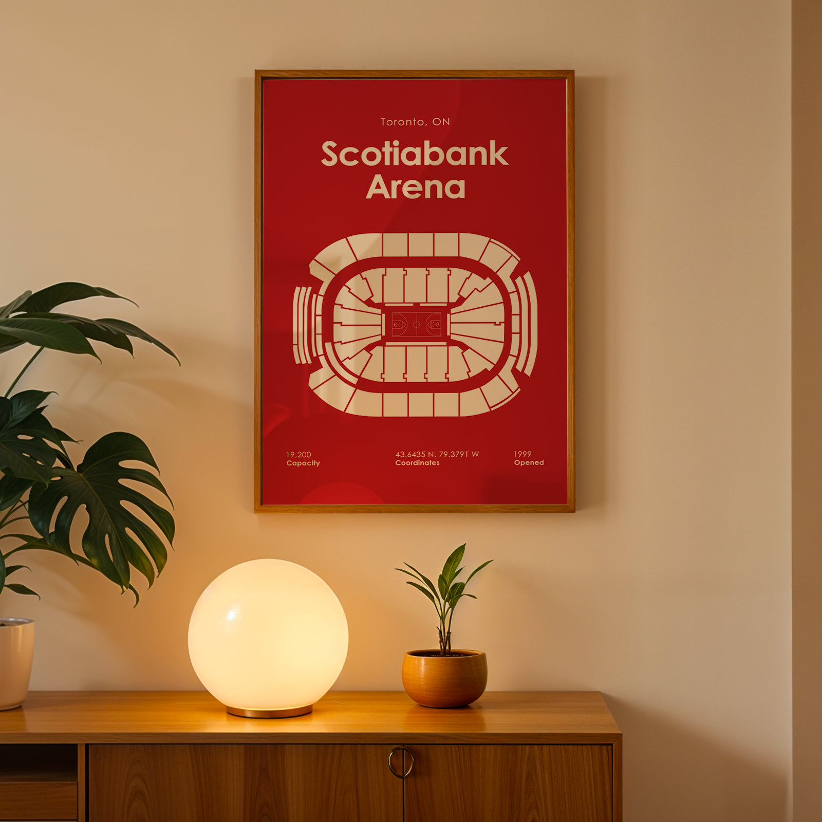 Framed poster of Scotiabank Arena on a wall with a plant and lamp below.