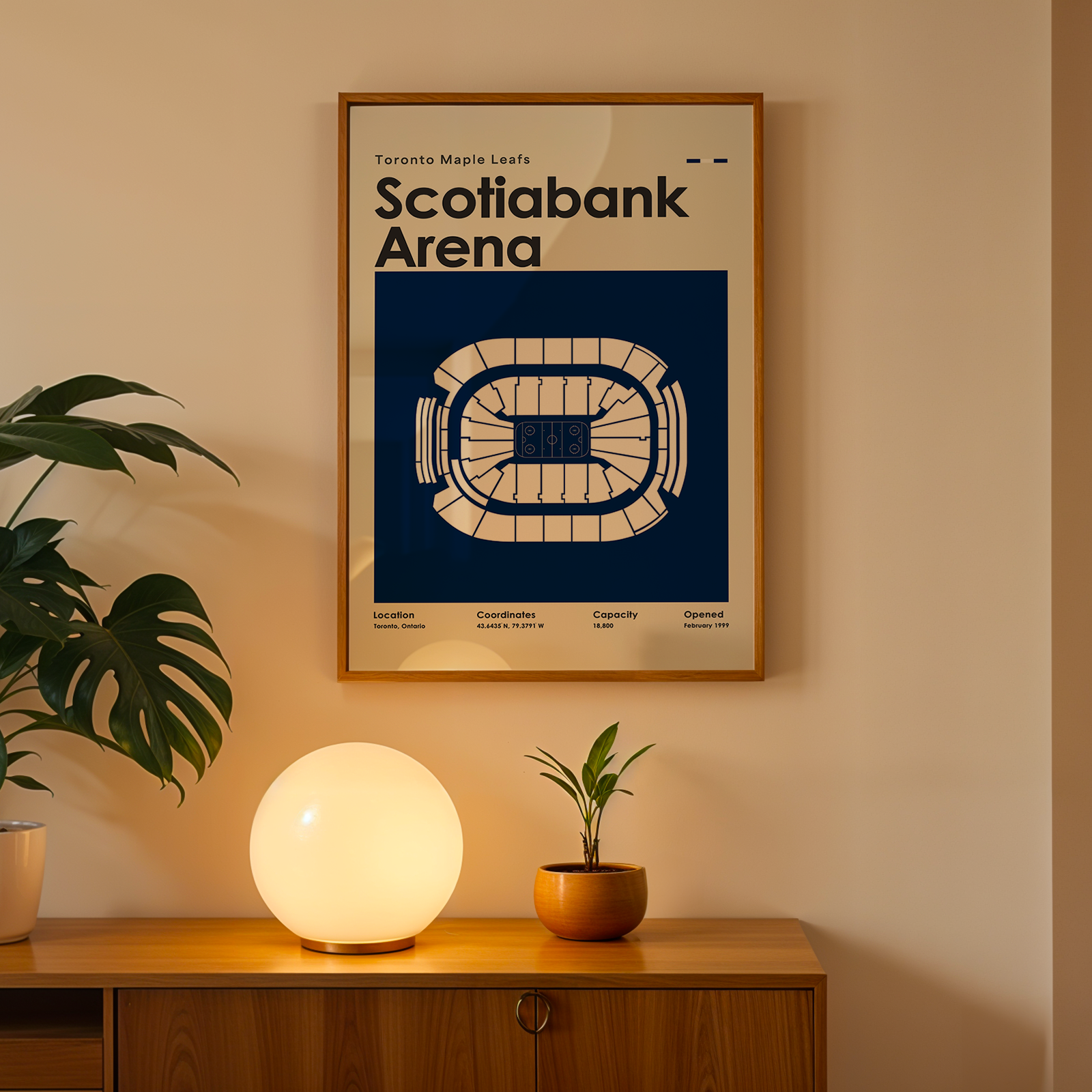 Framed poster of Scotiabank Arena on a wall above a wooden cabinet with decorative items.