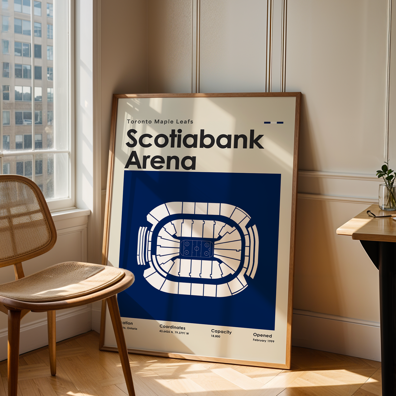 Framed poster of Scotiabank Arena in a room with a chair and table.