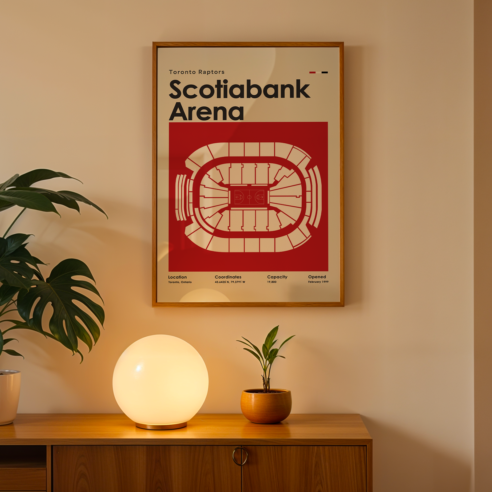 Framed poster of Scotiabank Arena on a wall above a wooden cabinet with decorative items.
