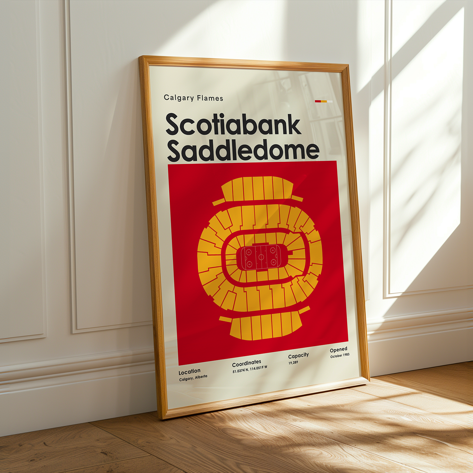 Framed poster of Scotiabank Saddledome with Calgary Flames logo on a wooden floor.