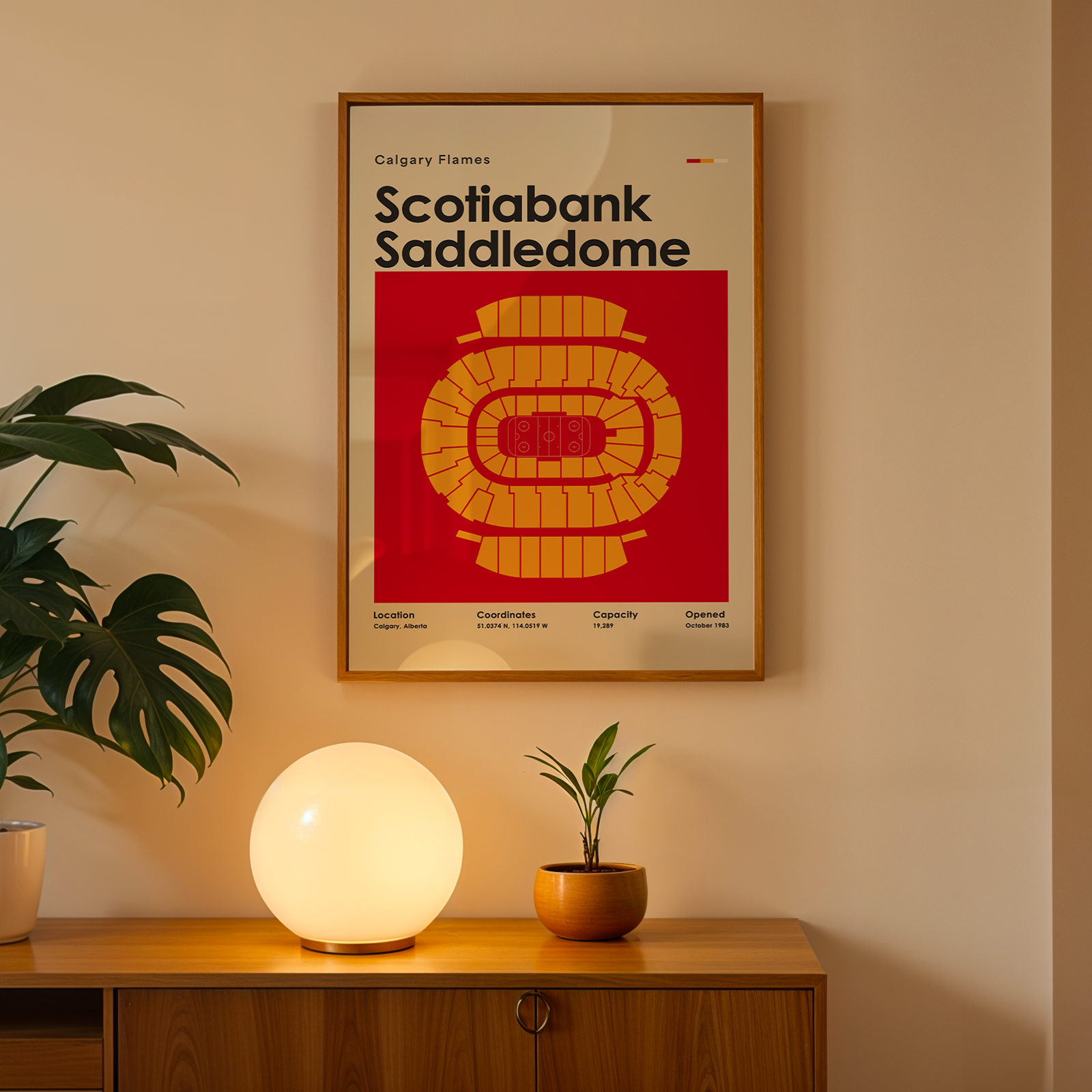Framed poster of Scotiabank Saddledome on a wall above a wooden cabinet with decorative items.