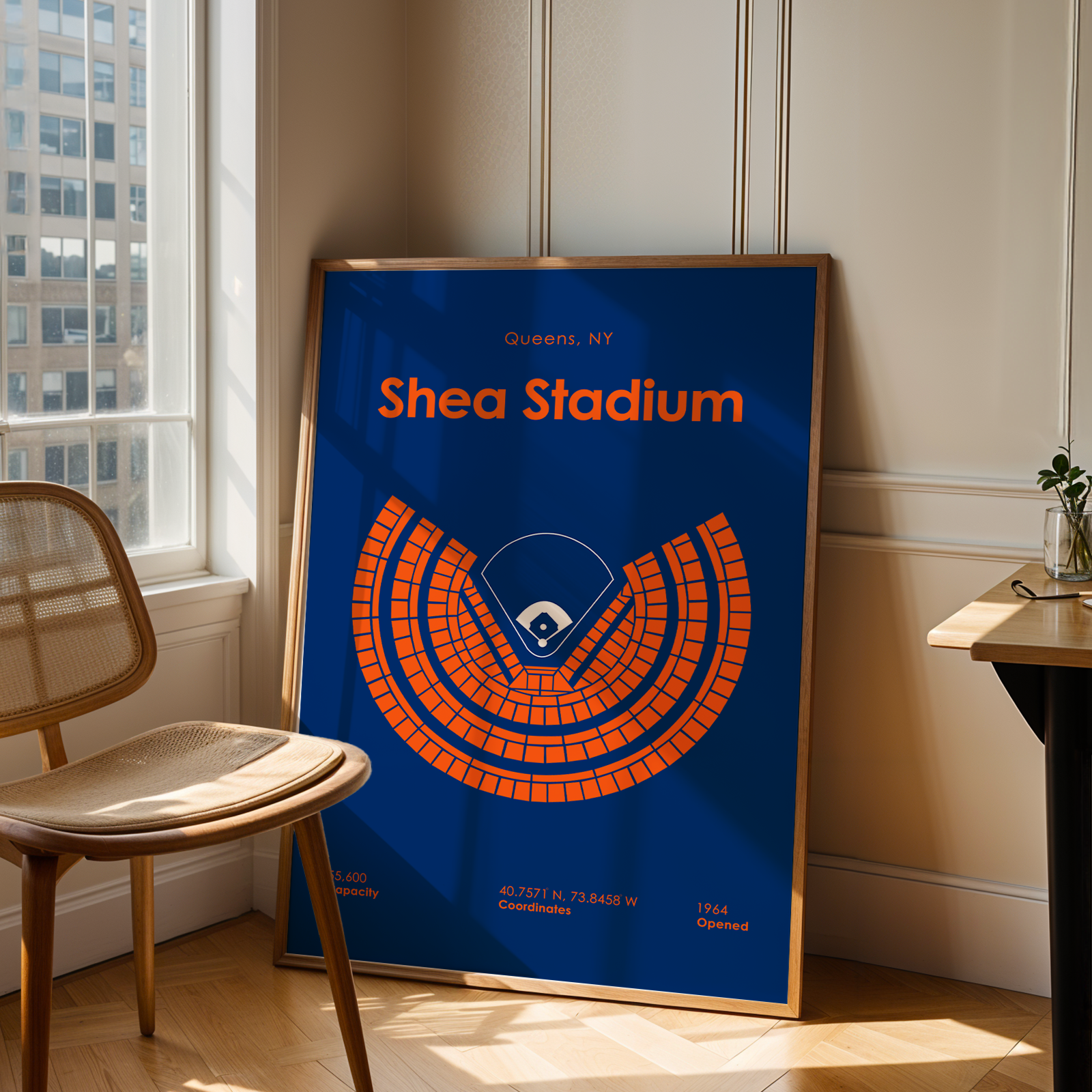 Framed poster of Shea Stadium in a room with a chair and table.