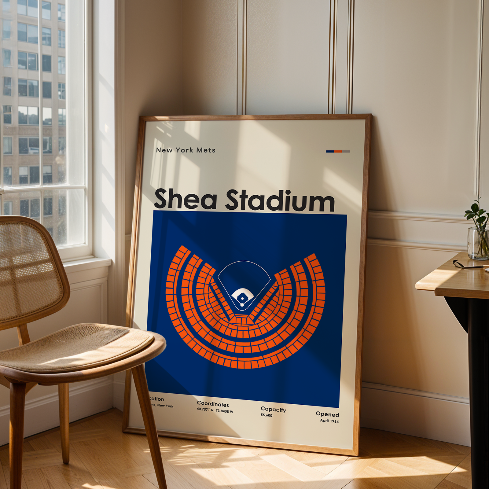 Framed poster of Shea Stadium in a room with a chair and table.