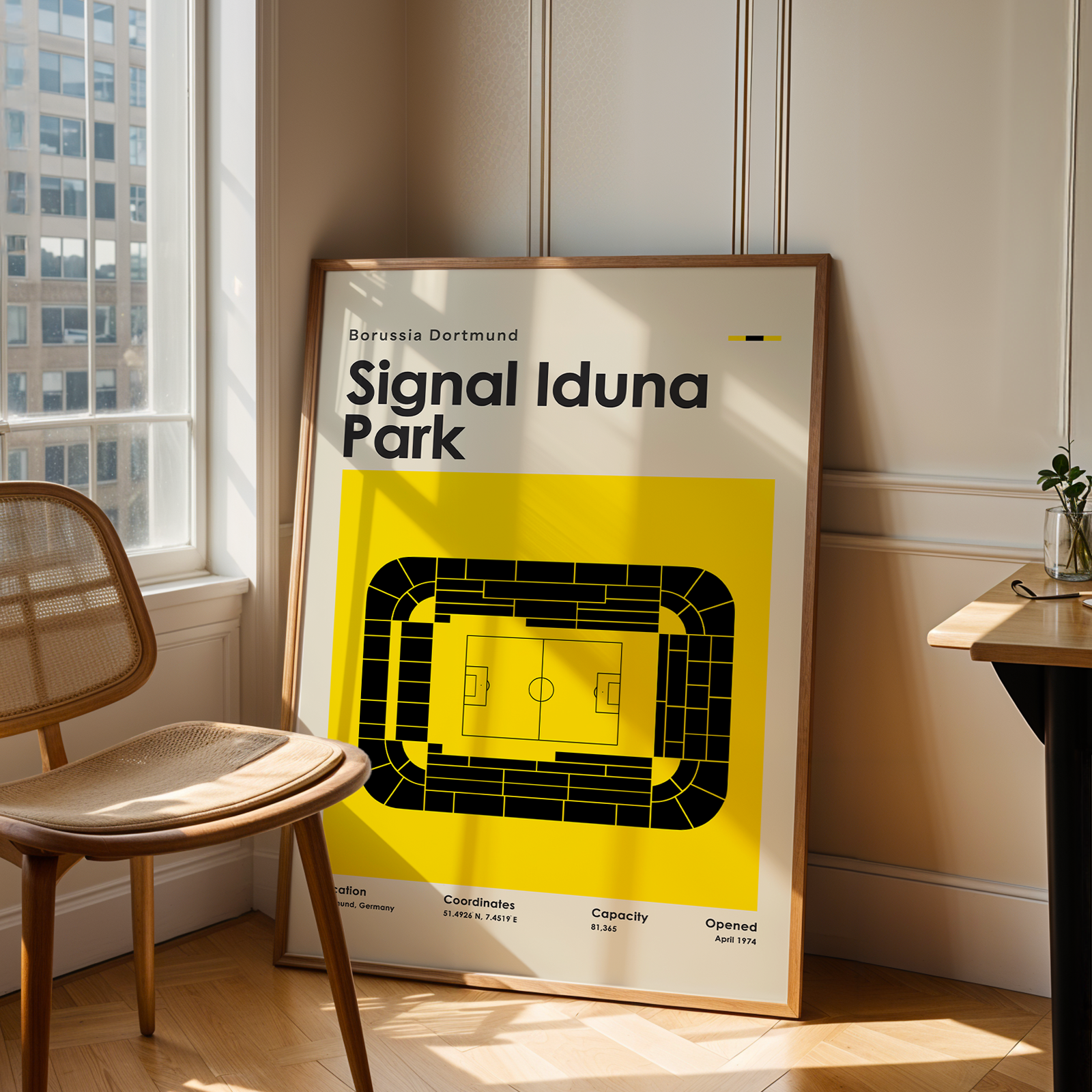 Framed poster of Signal Iduna Park in a room with a chair and window.