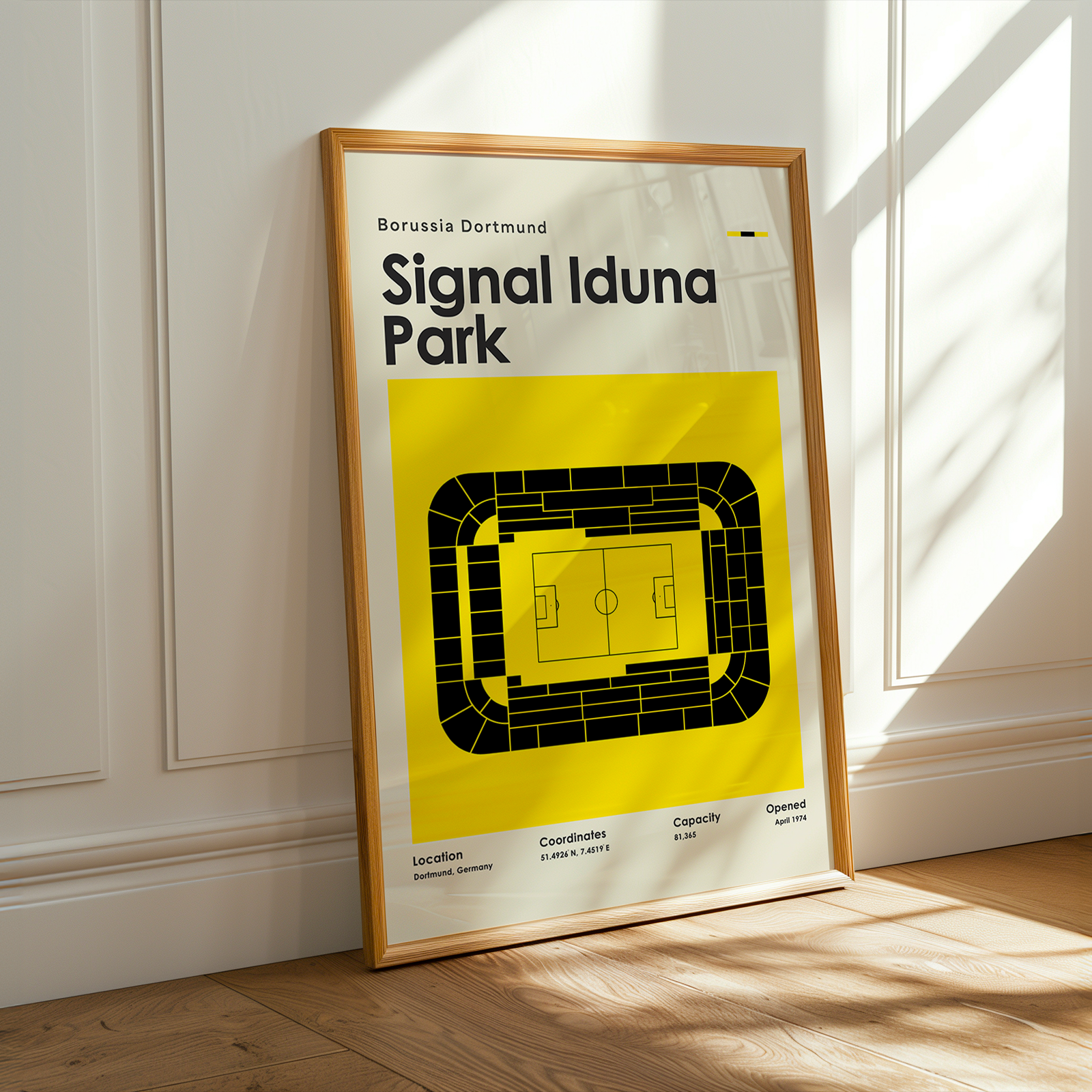 Framed poster of Signal Iduna Park with a yellow and black design, placed on a wooden floor.